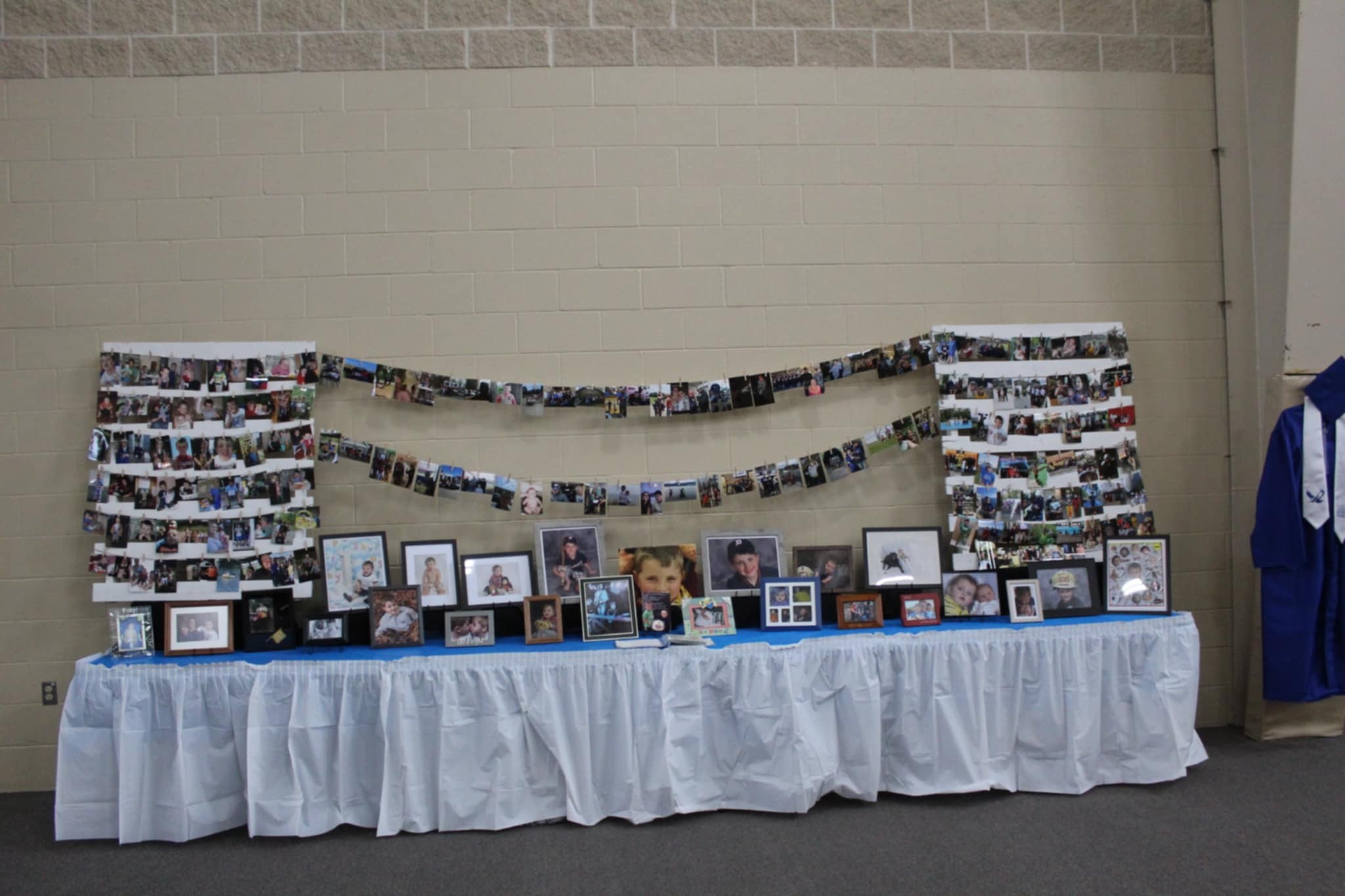 Table display featuring numerous framed personal photographs and strings of hanging photos for a graduation celebration.