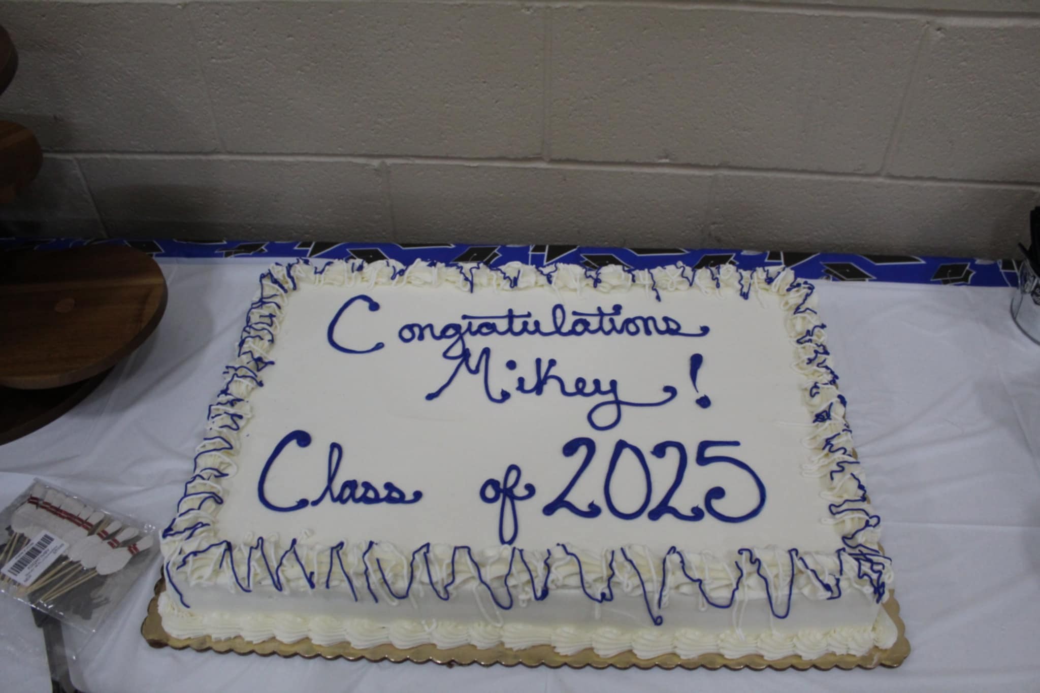 Rectangular sheet cake with white frosting and blue icing reading Congratulations Mikey! Class of 2025