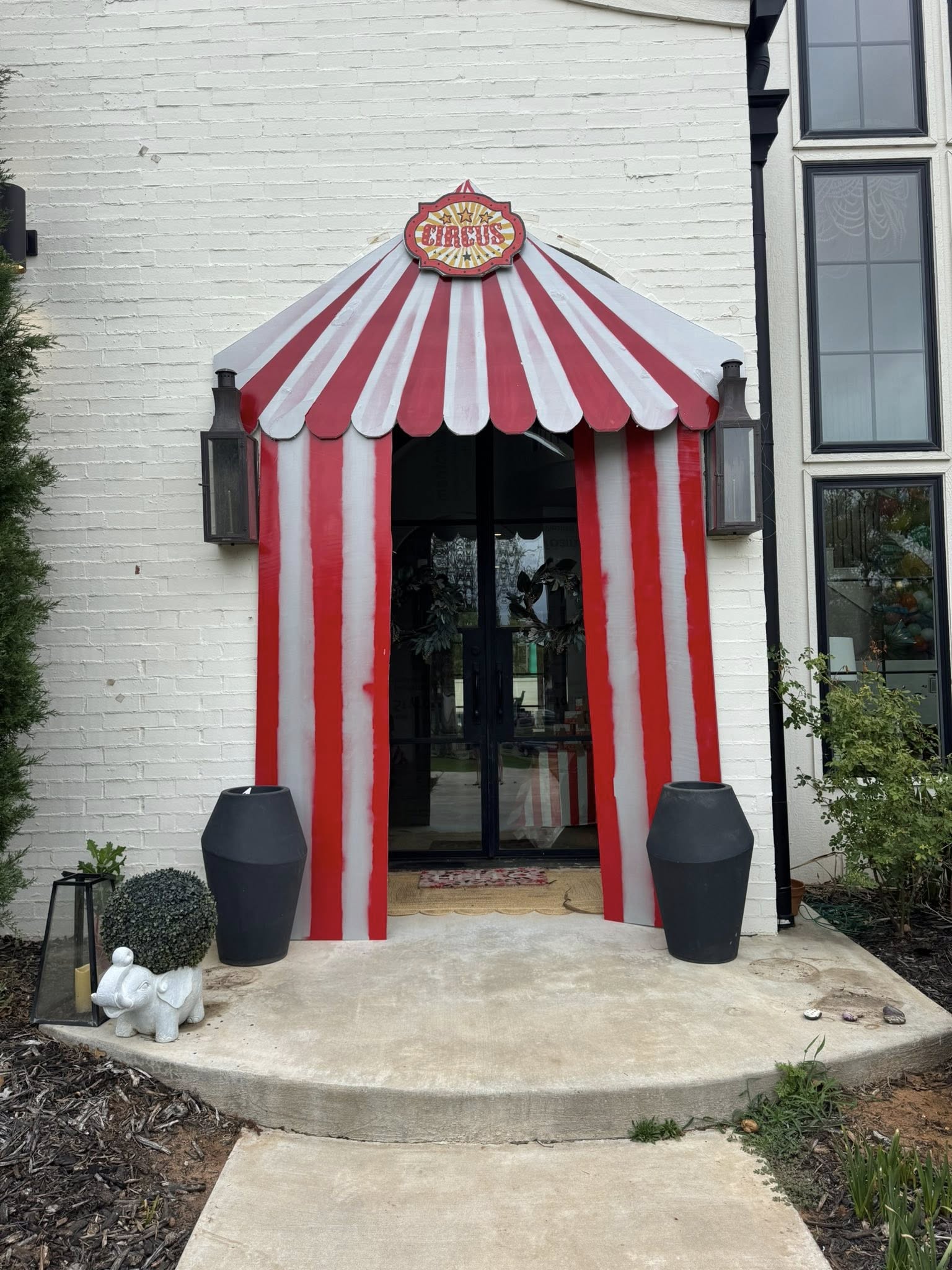 Front door decorated with a red and white striped circus tent awning and sign.