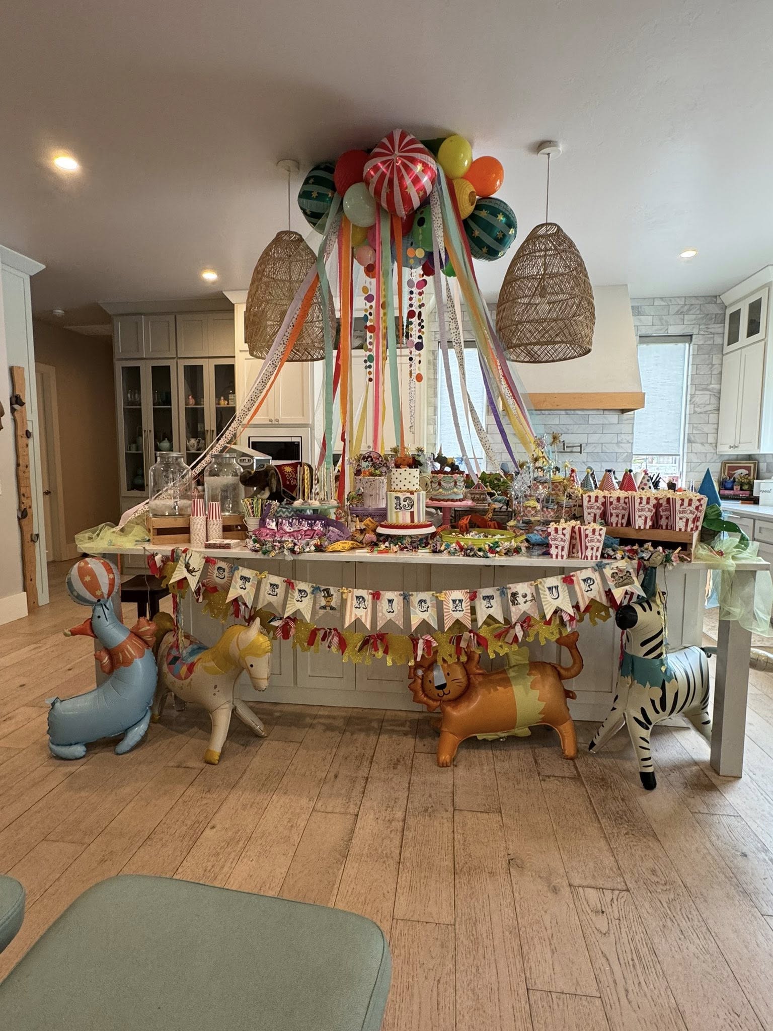 Kitchen island decorated for a circus themed 13th birthday party with balloons, circus animals, and candy.