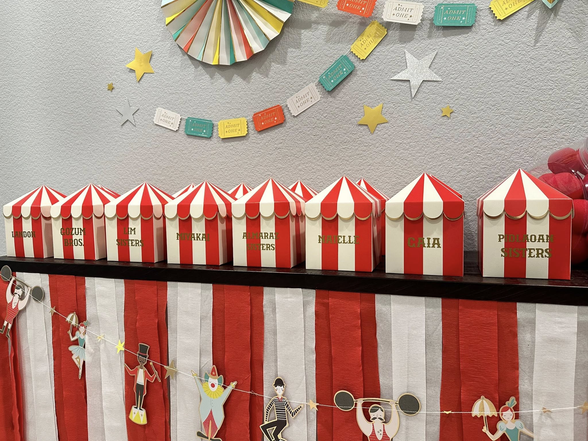 Personalized red and white circus tent treat boxes lined up for a carnival themed party.