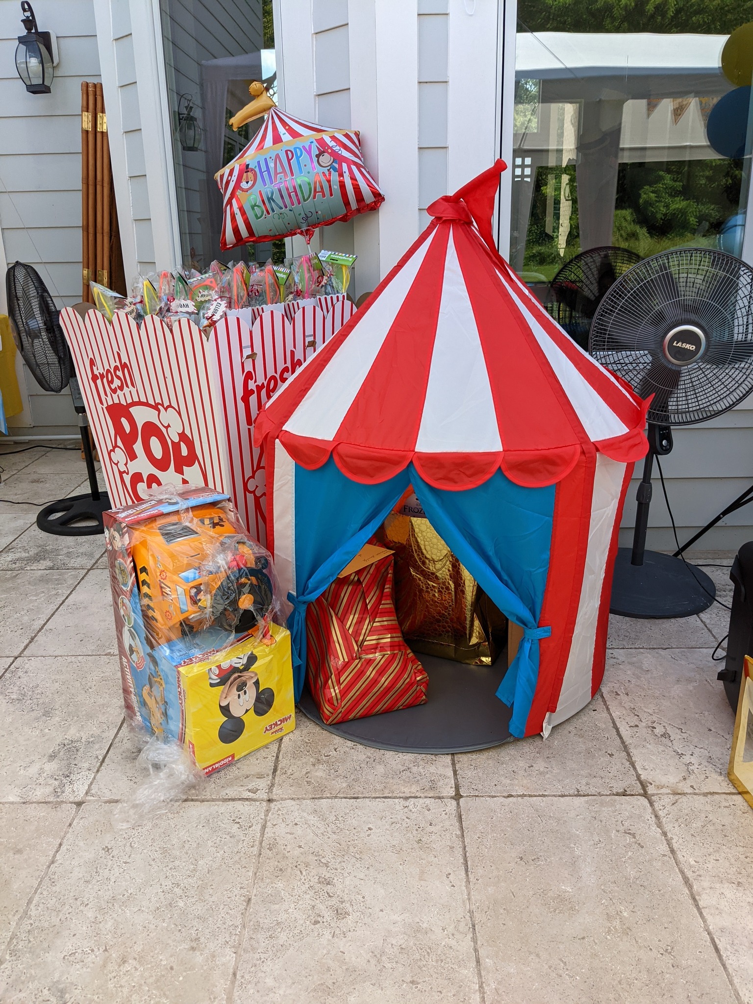 Carnival-themed kids play tent with red and white stripes next to a popcorn-shaped gift display.
