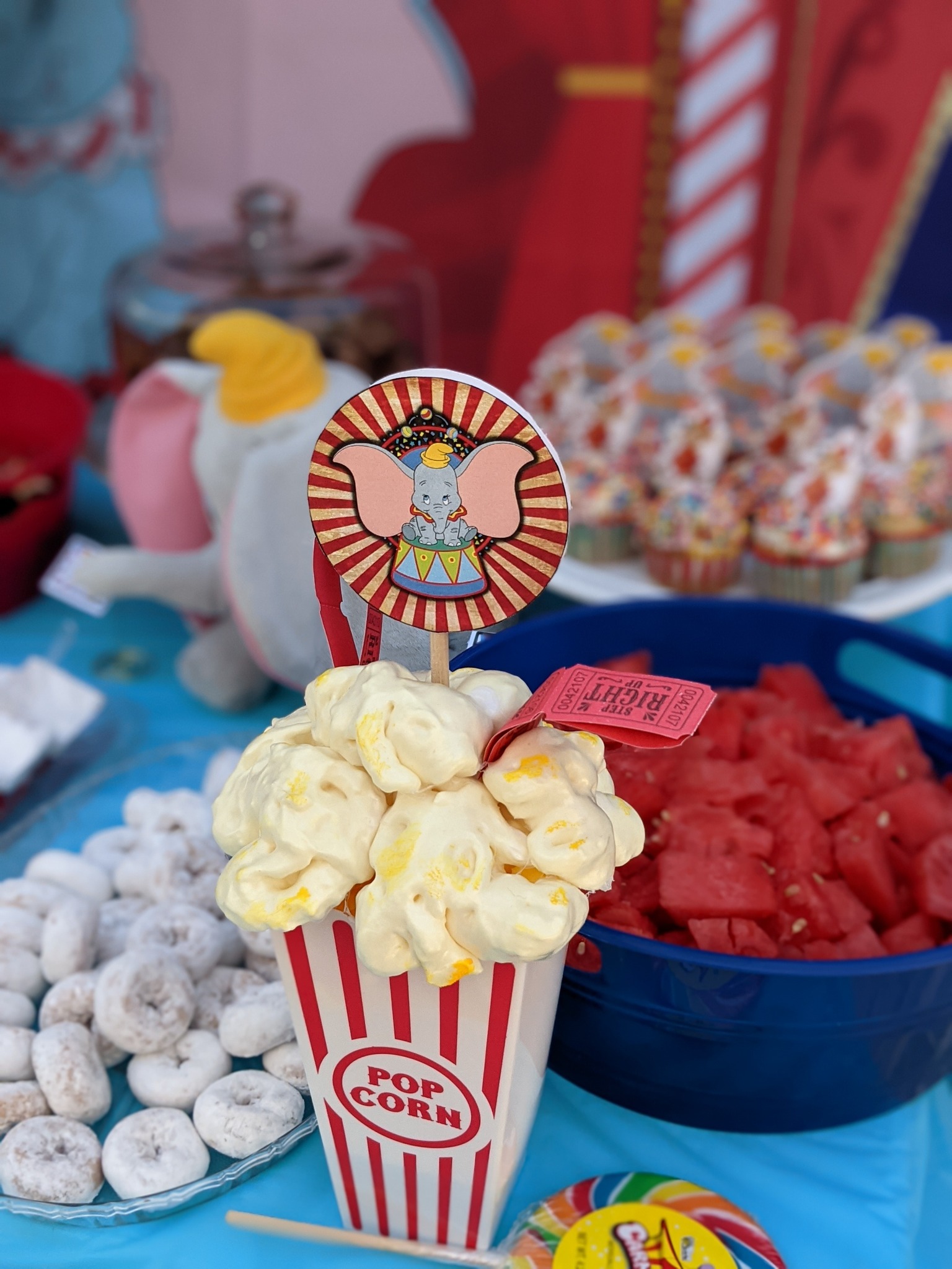 Popcorn box topper featuring a Dumbo illustration on a circus-themed party table.