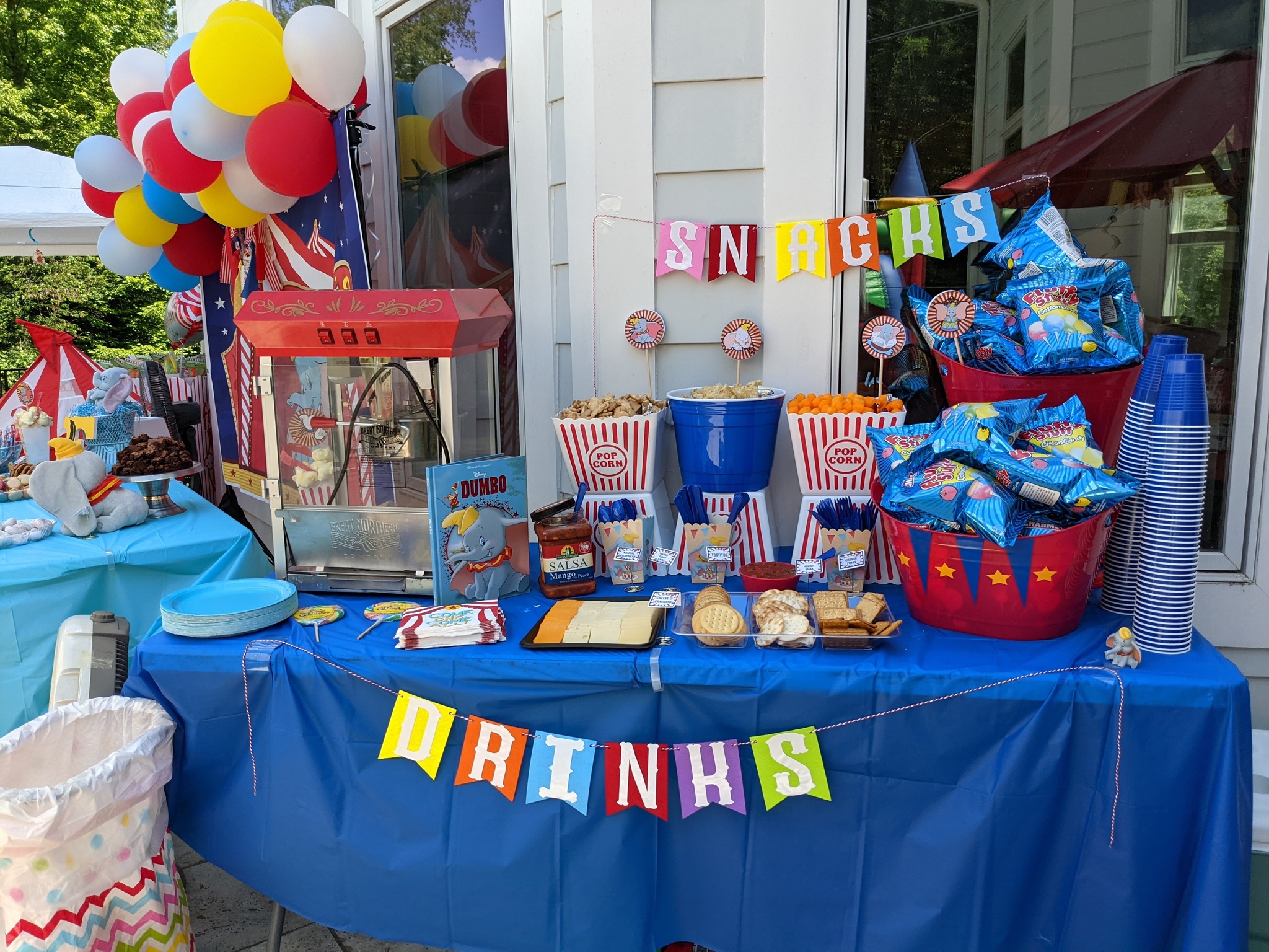 Dumbo-themed party snack table featuring popcorn, cotton candy bags, and colorful party decorations.