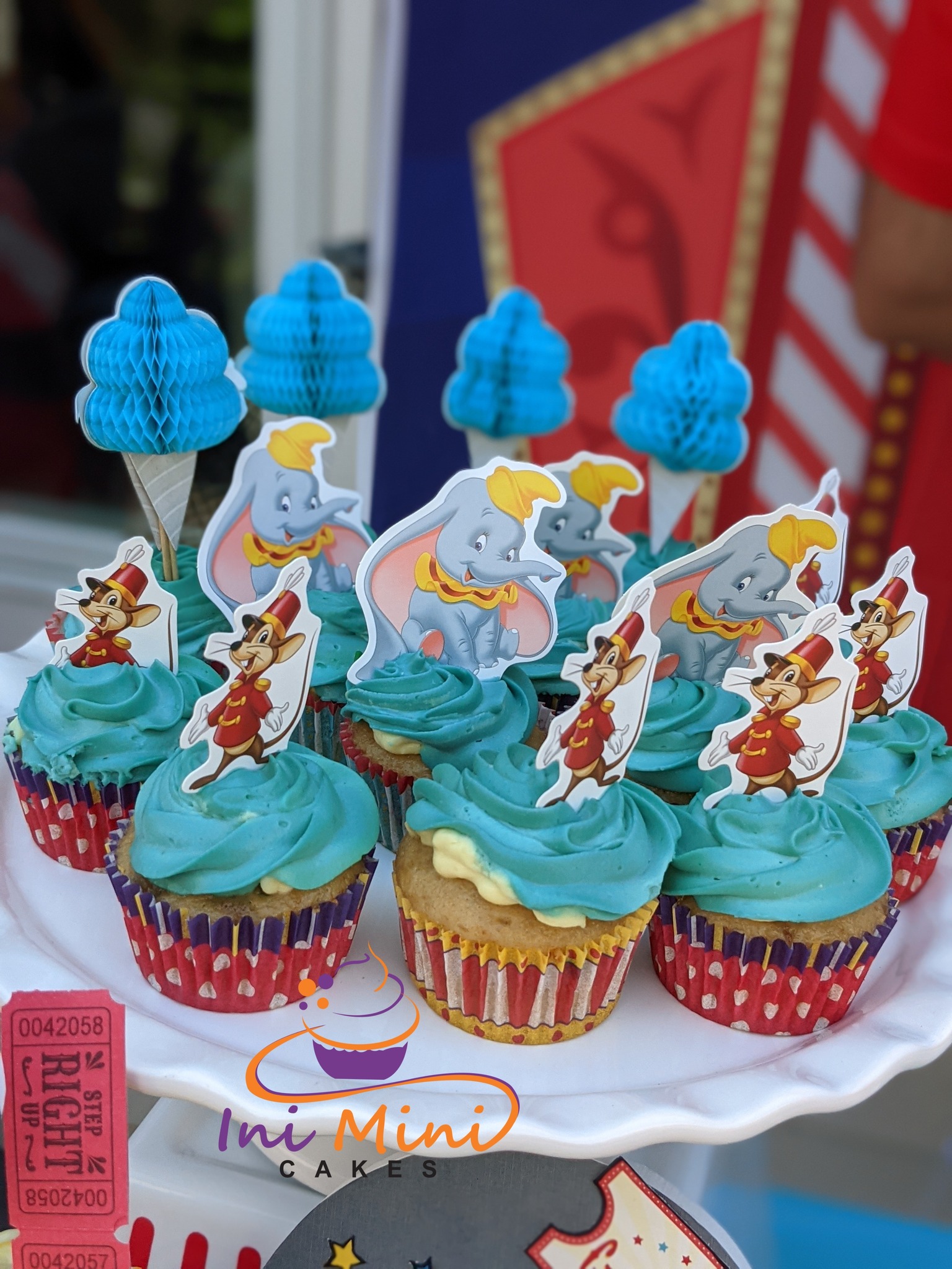 Dumbo and Timothy Mouse themed cupcakes with blue swirl frosting and circus tent decorations.