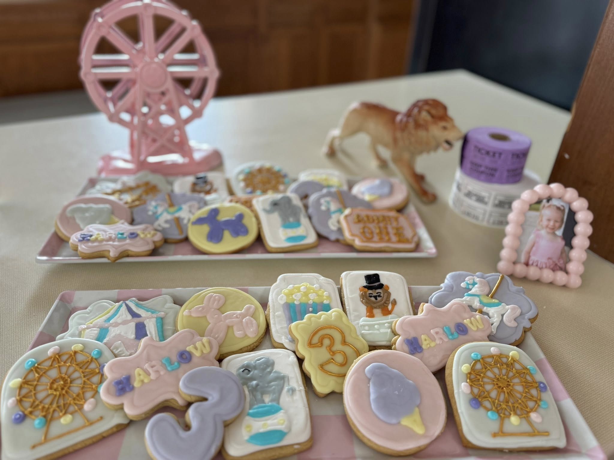 Assorted circus-themed decorated cookies for a third birthday, featuring ferris wheels, animals, and the name Harlow.