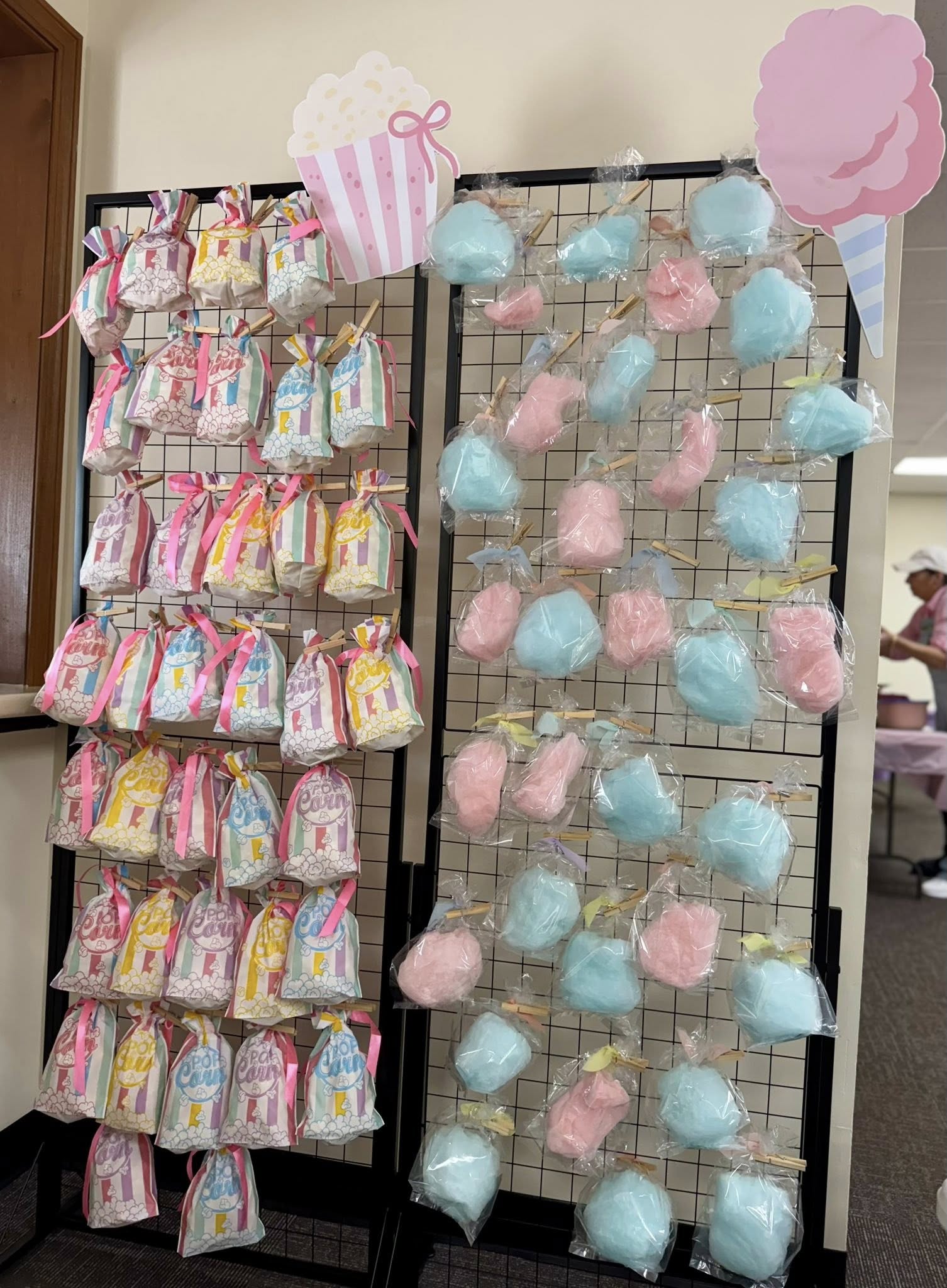 Display rack holding individually packaged bags of popcorn and cones of blue and pink cotton candy.