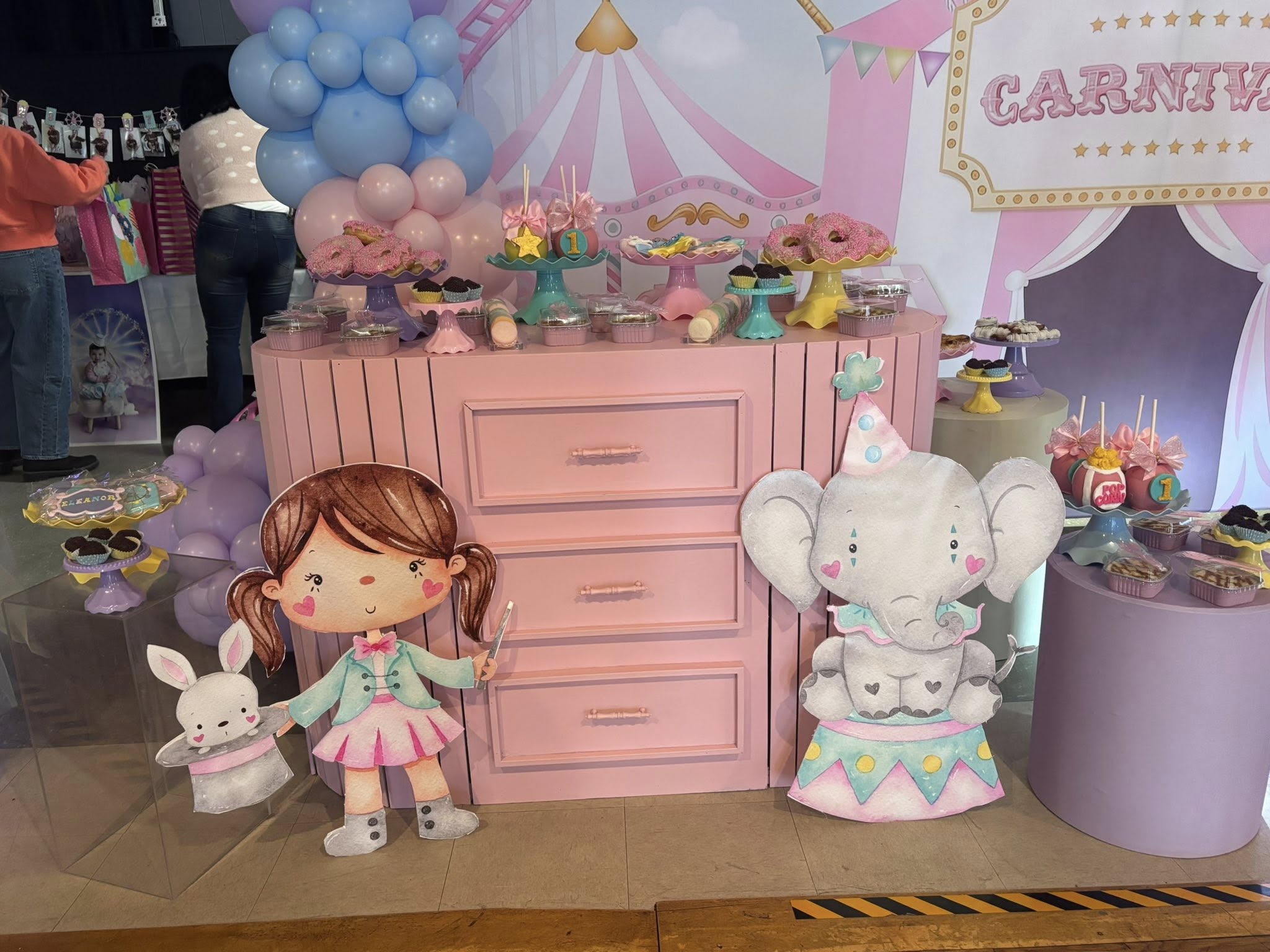 Carnival themed birthday dessert table with pink dresser, elephant cutout, and magician girl illustration