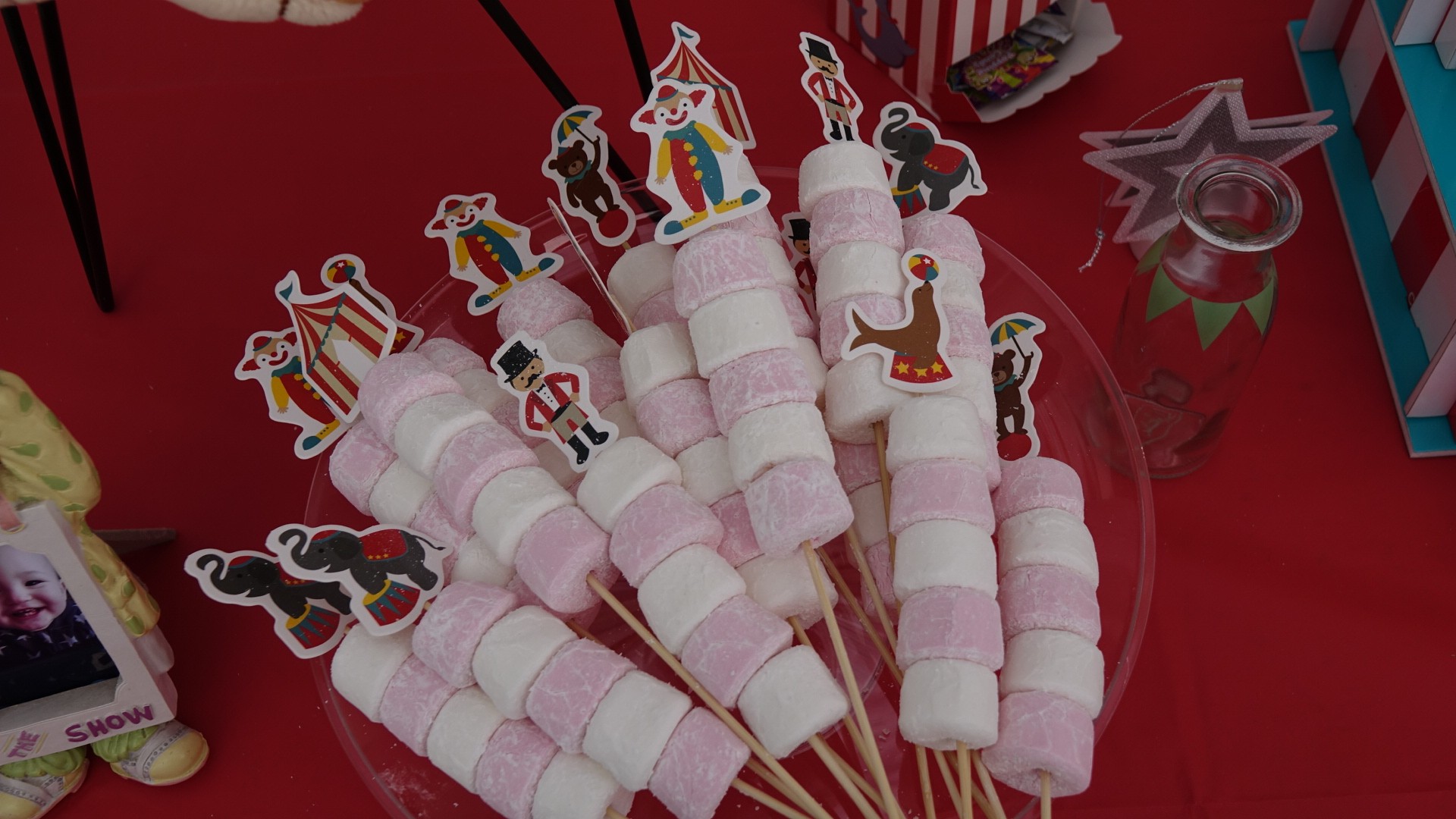 Pink and white marshmallow skewers decorated with circus-themed toppers on a platter