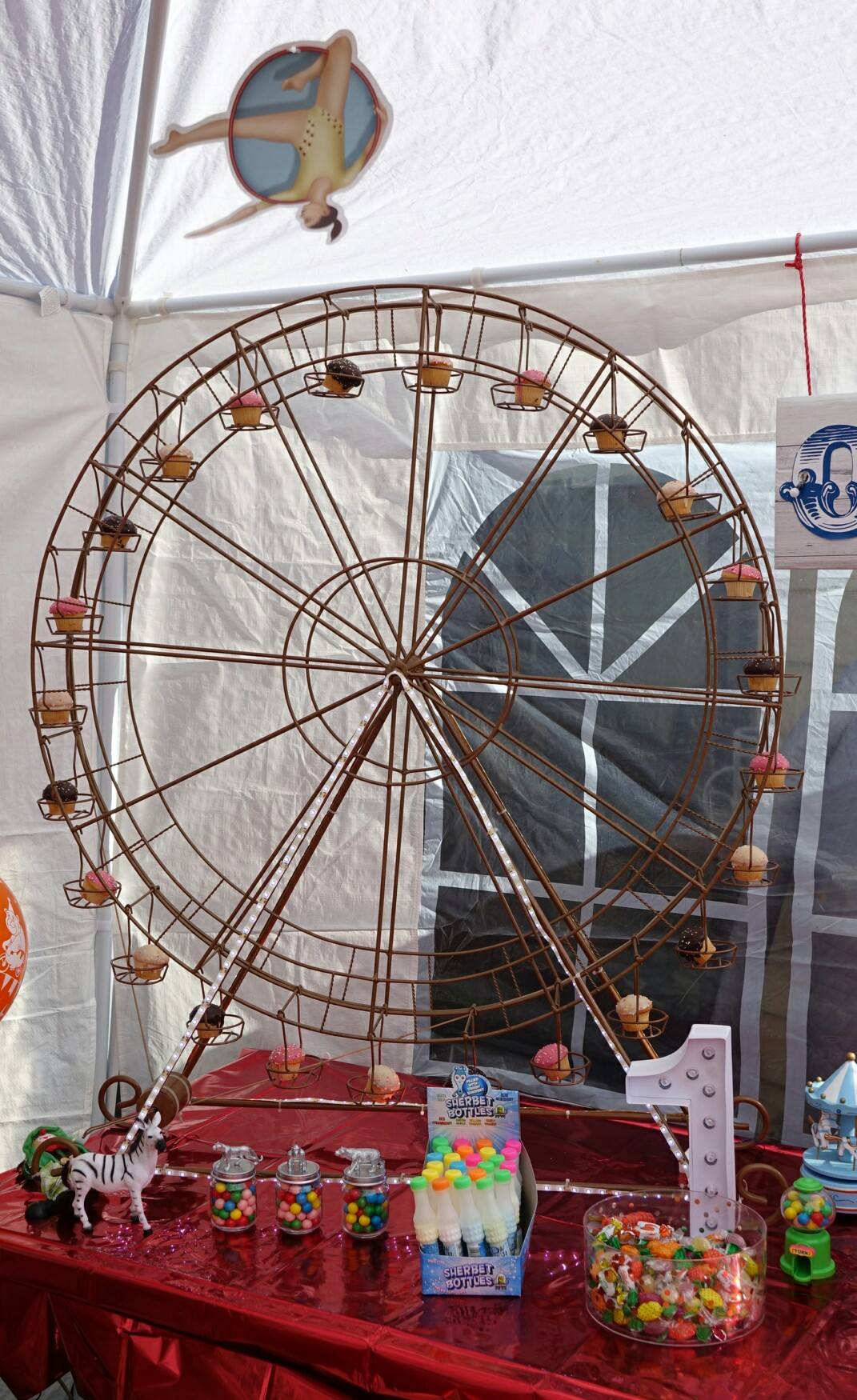 Metal Ferris wheel cupcake stand displayed on a party table with assorted candies