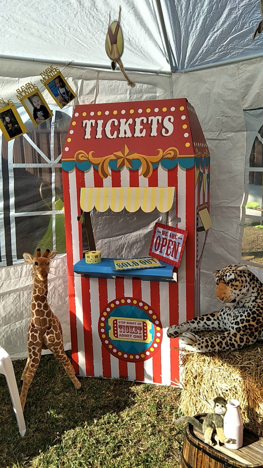 Cardboard circus ticket booth decoration for a party with stuffed giraffe and leopard animals