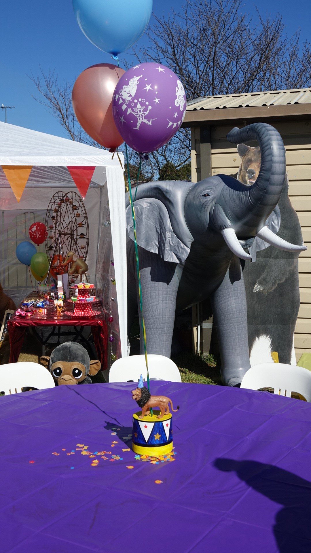 Table set for a circus themed party with a purple tablecloth and a lion toy centerpiece.
