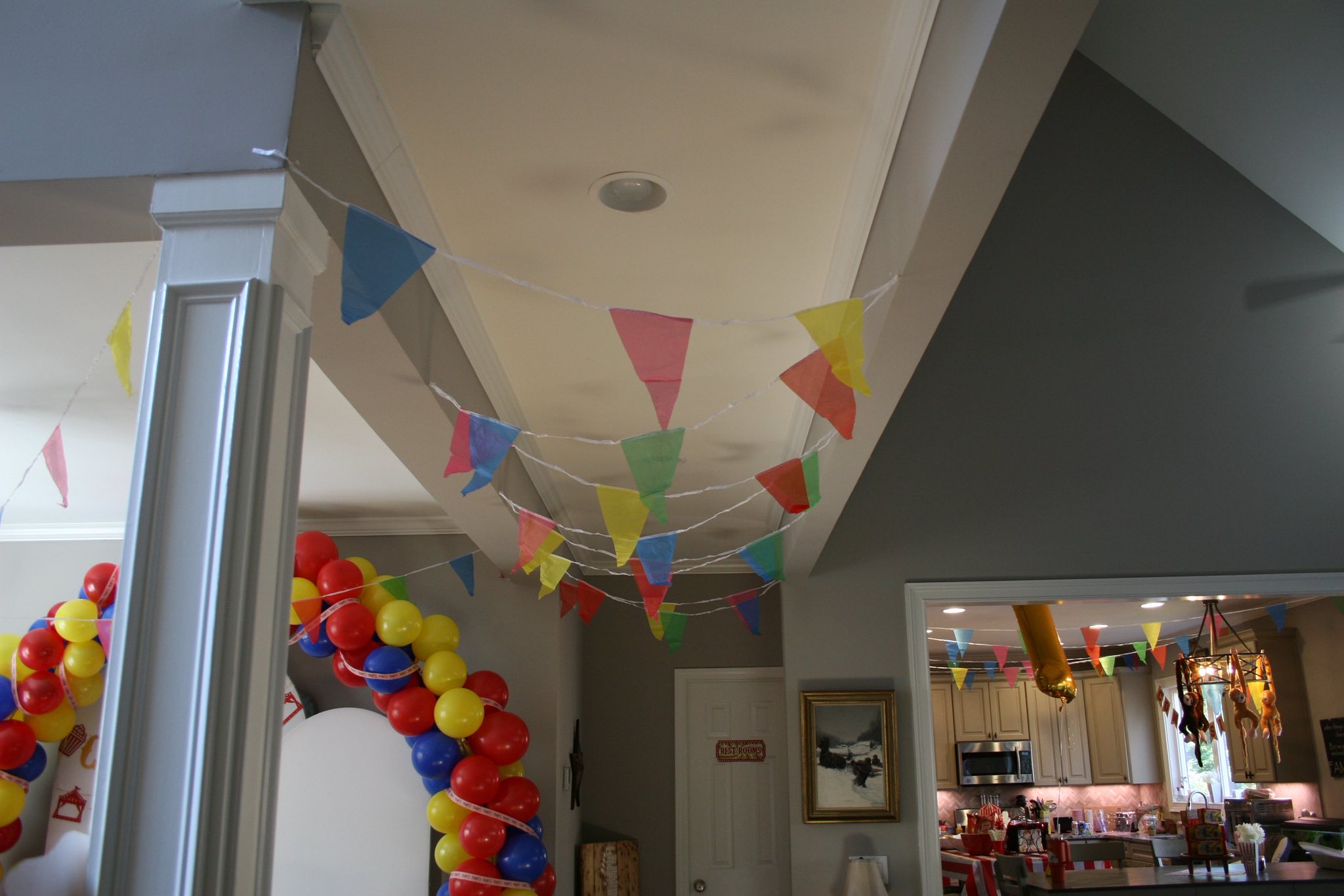 Colorful pennant banner hanging from a ceiling with a balloon arch in the foreground