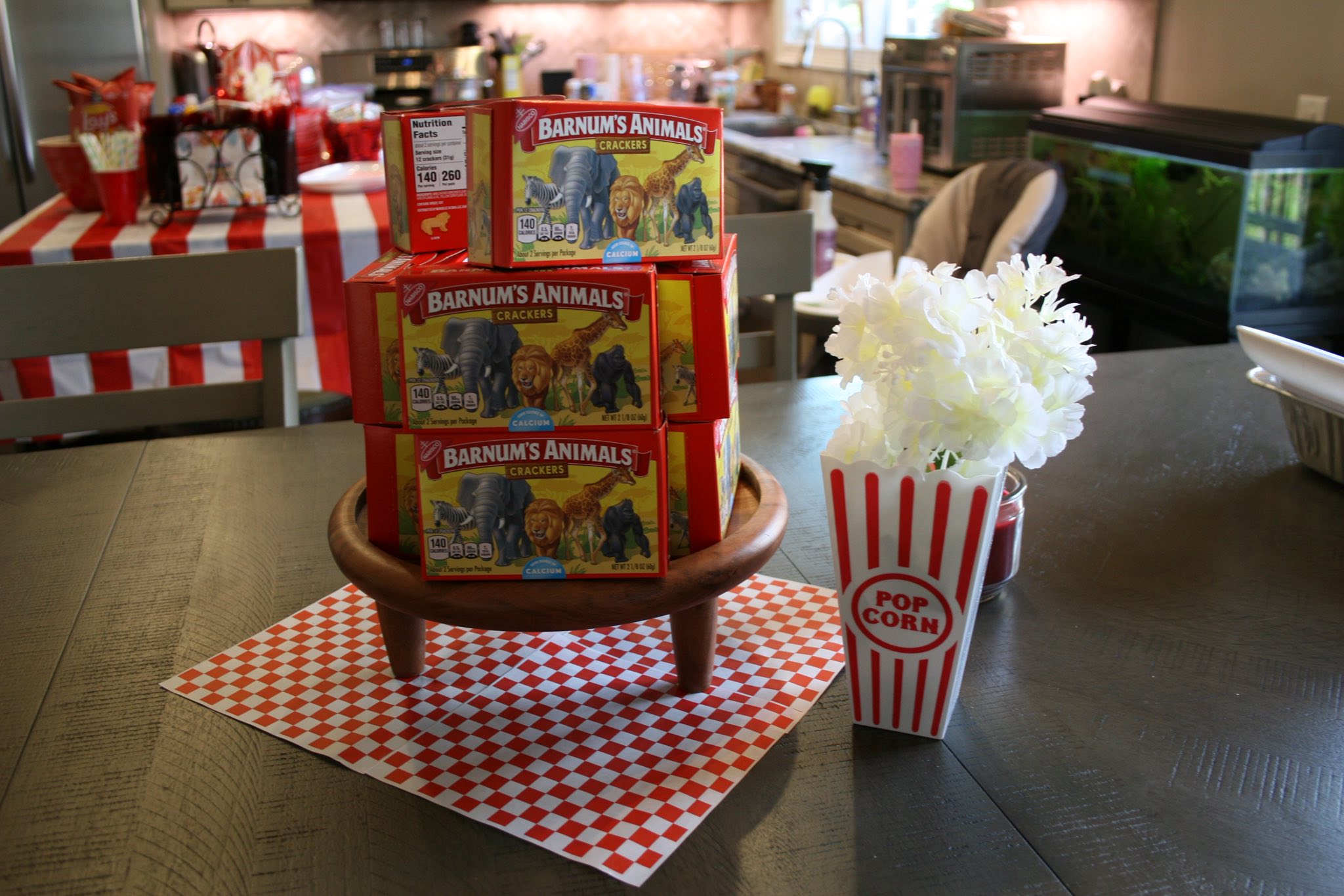 Stack of Barnum's Animals Crackers boxes on a wooden pedestal displayed on a kitchen table.
