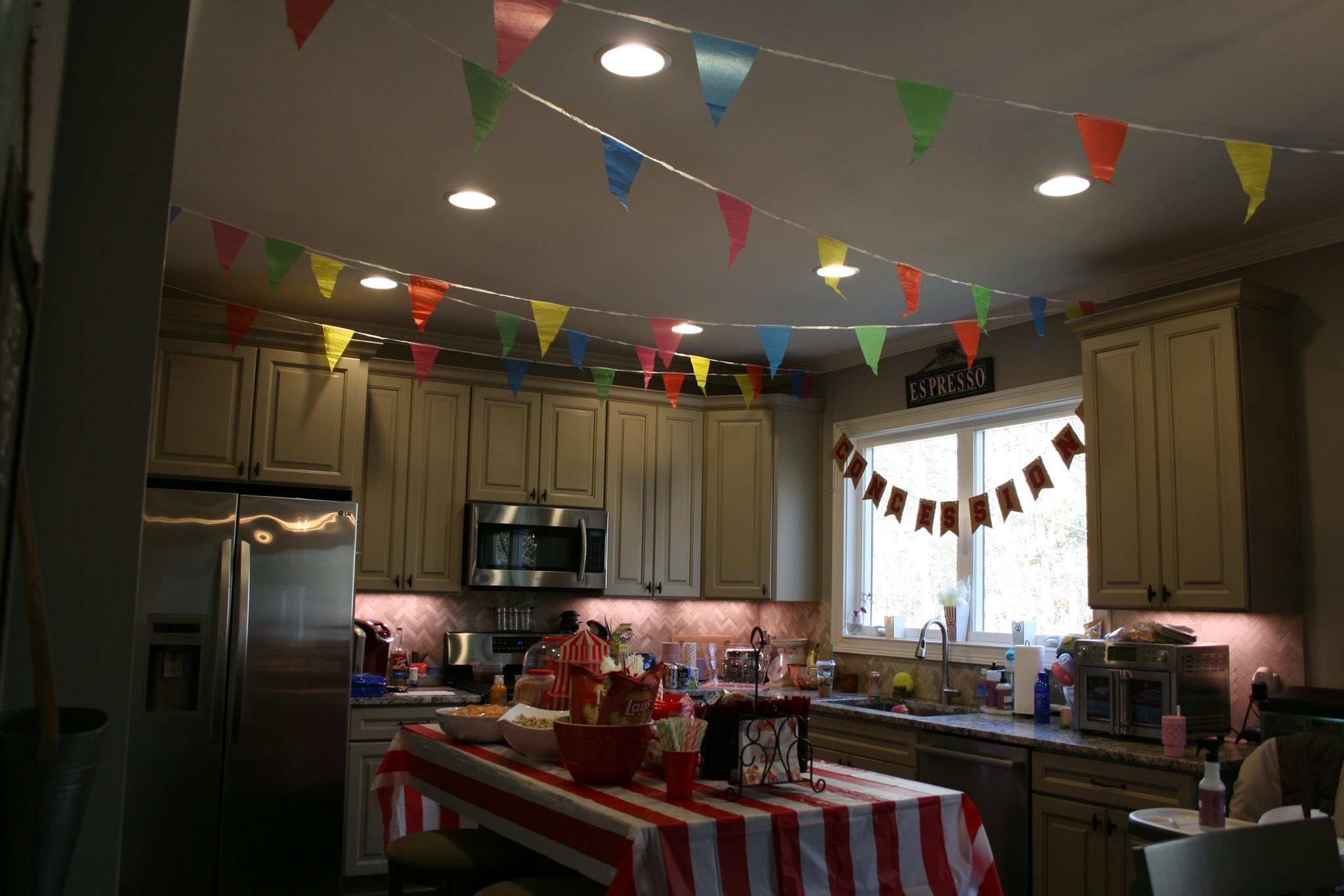 Kitchen decorated for a carnival theme with colorful bunting and a red and white striped table cover.