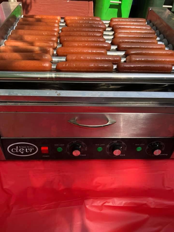 Clevr commercial hot dog roller grill machine with multiple sausages cooking on the stainless steel racks