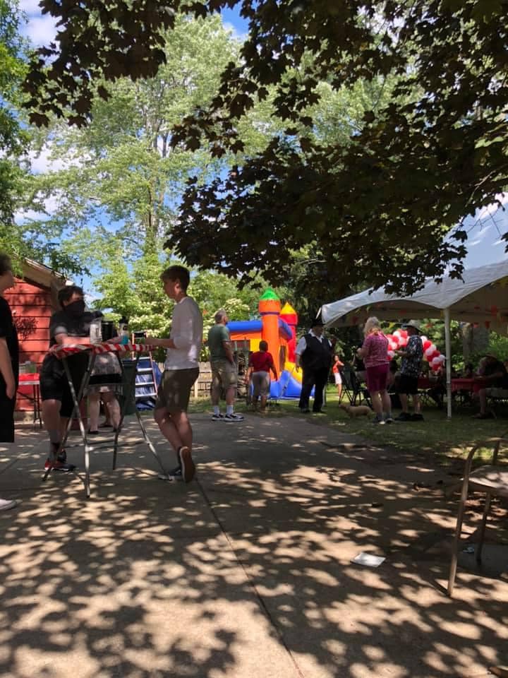 Outdoor family gathering with an inflatable bounce house and party tent in a backyard