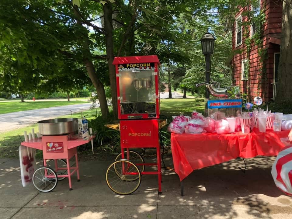 Concession stand setup featuring a popcorn machine, cotton candy machine, and sno-cone machine on an outdoor patio.