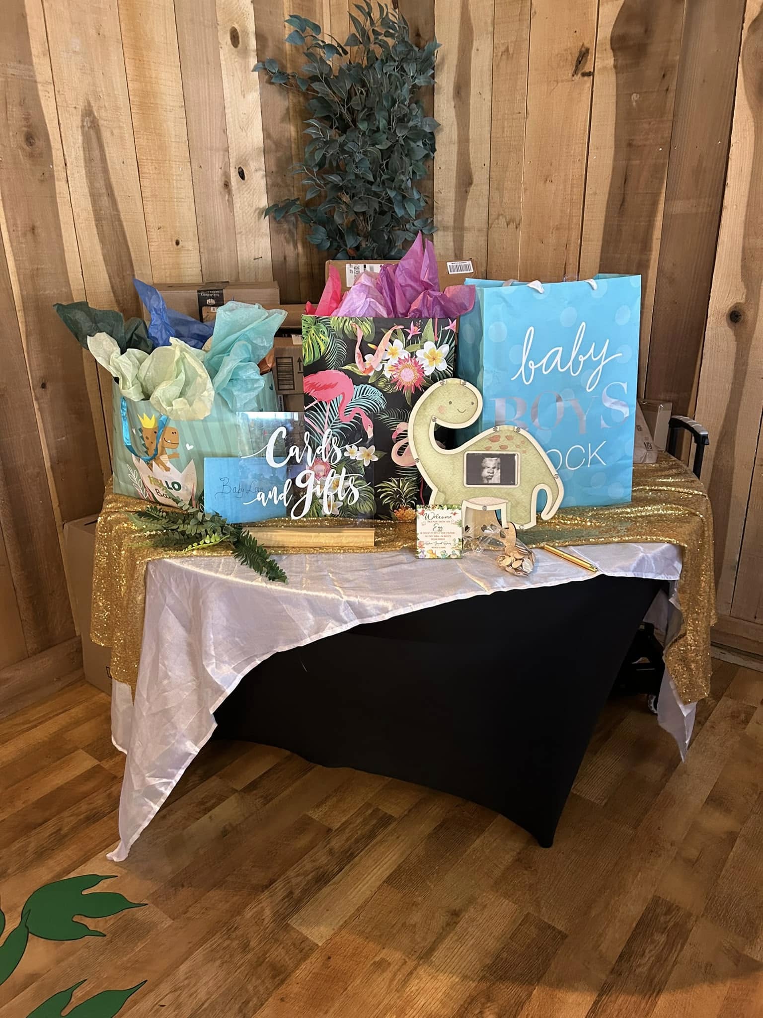 Table with baby shower cards and gifts adorned with a dinosaur sign