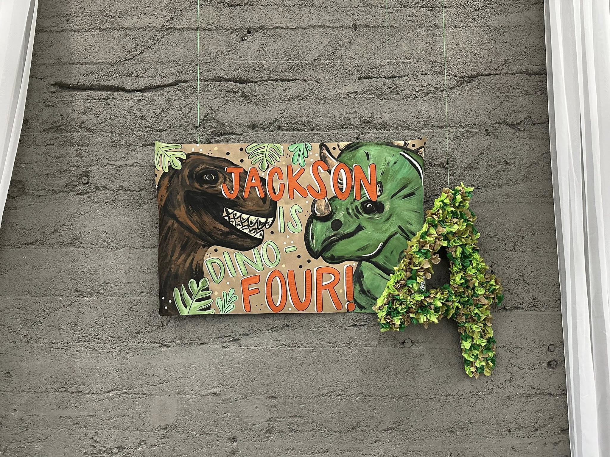 Custom Jackson is Dino Four birthday sign with painted dinosaurs and a floral number four backdrop.