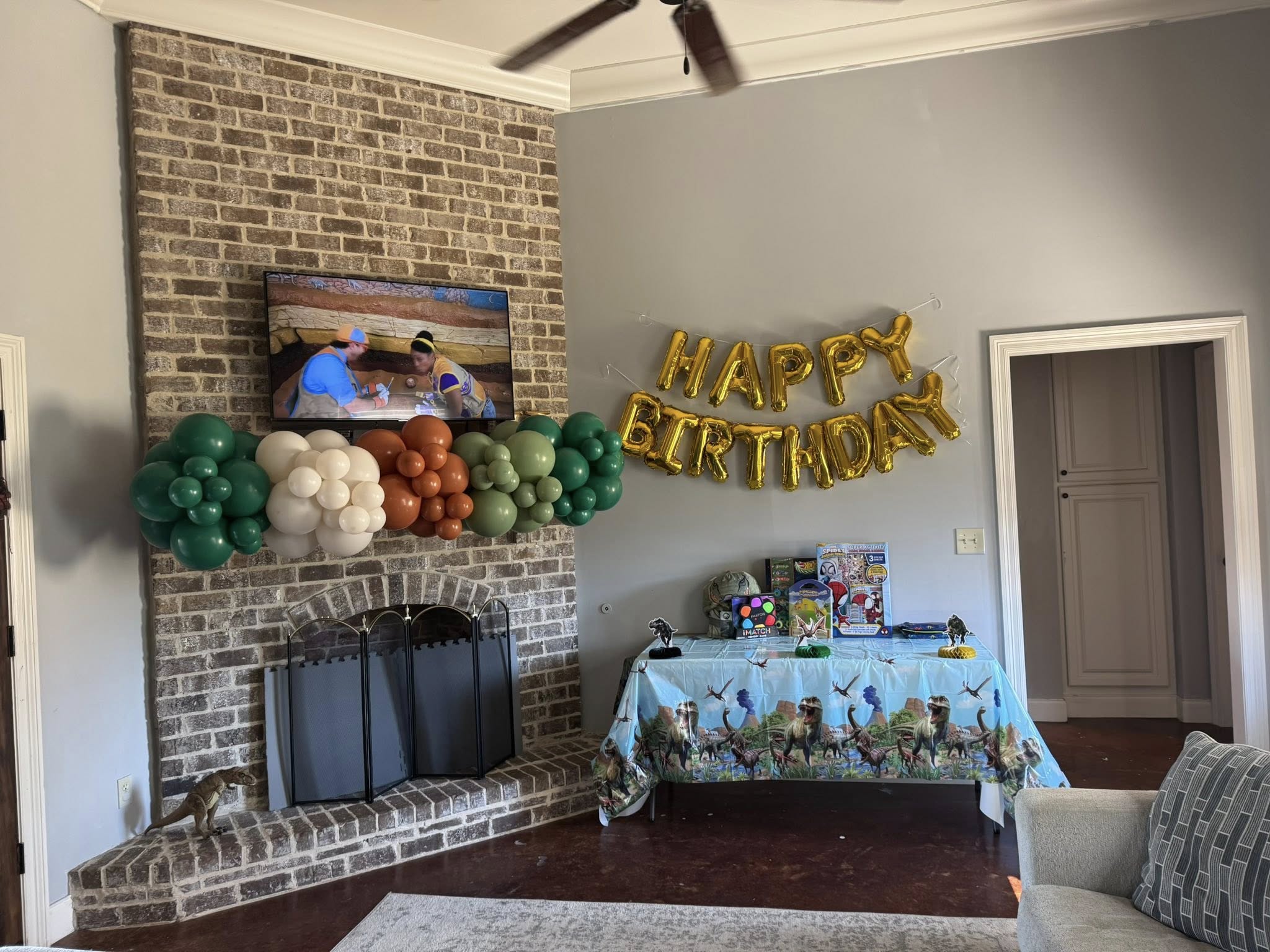 Dinosaur-themed birthday party decorations with a festive table and Happy Birthday balloons.