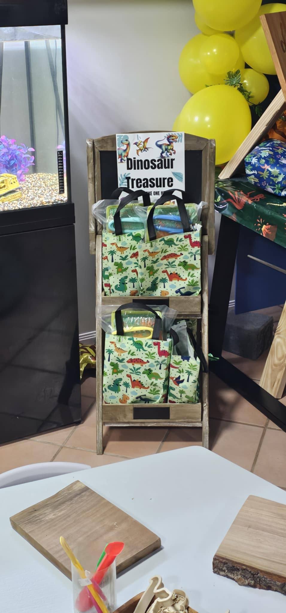 Dinosaur themed favor bags displayed on a wooden stand marked Dinosaur Treasure.