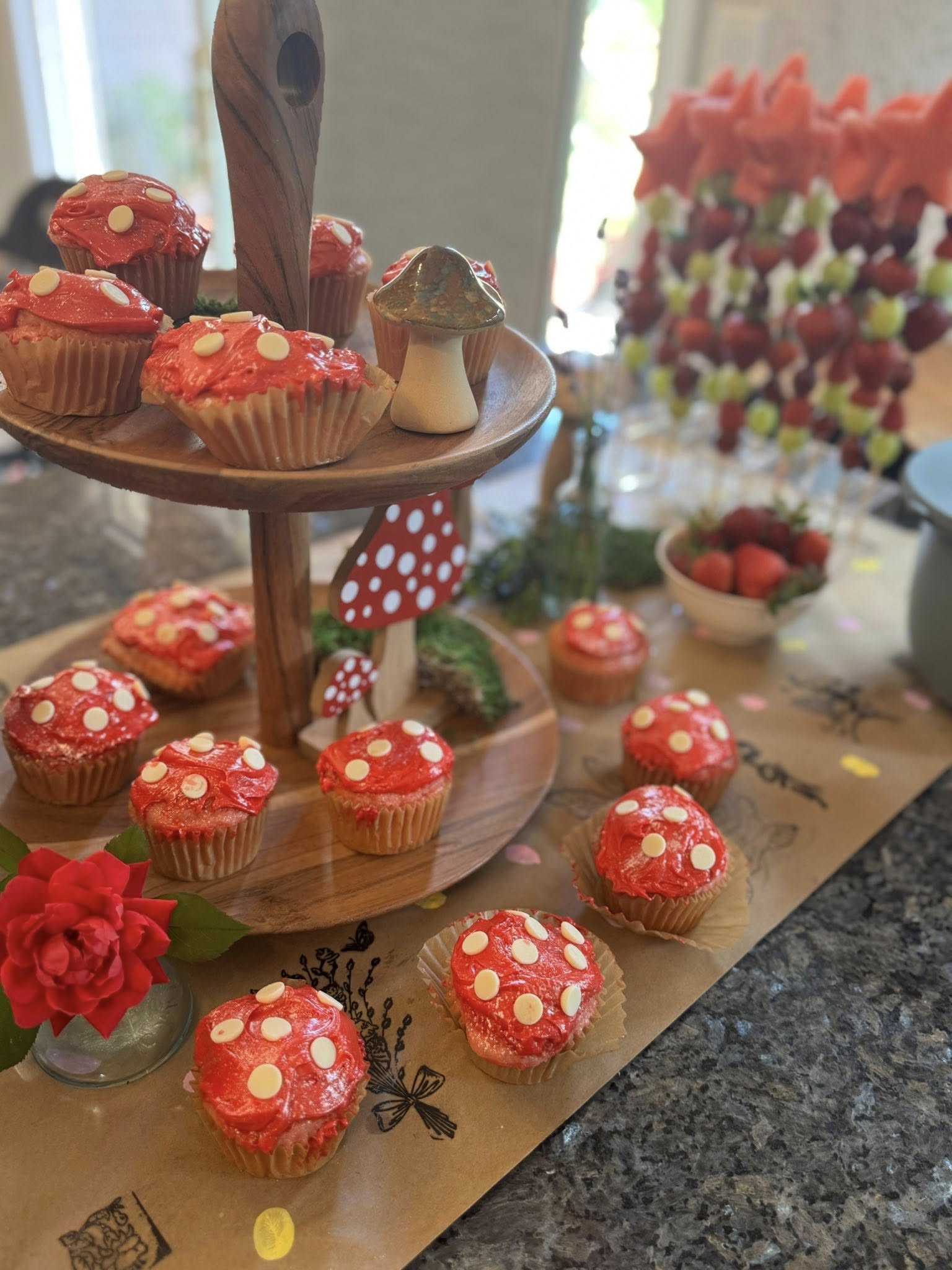Tiered stand featuring mushroom-themed cupcakes with red frosting and white chocolate dot accents.