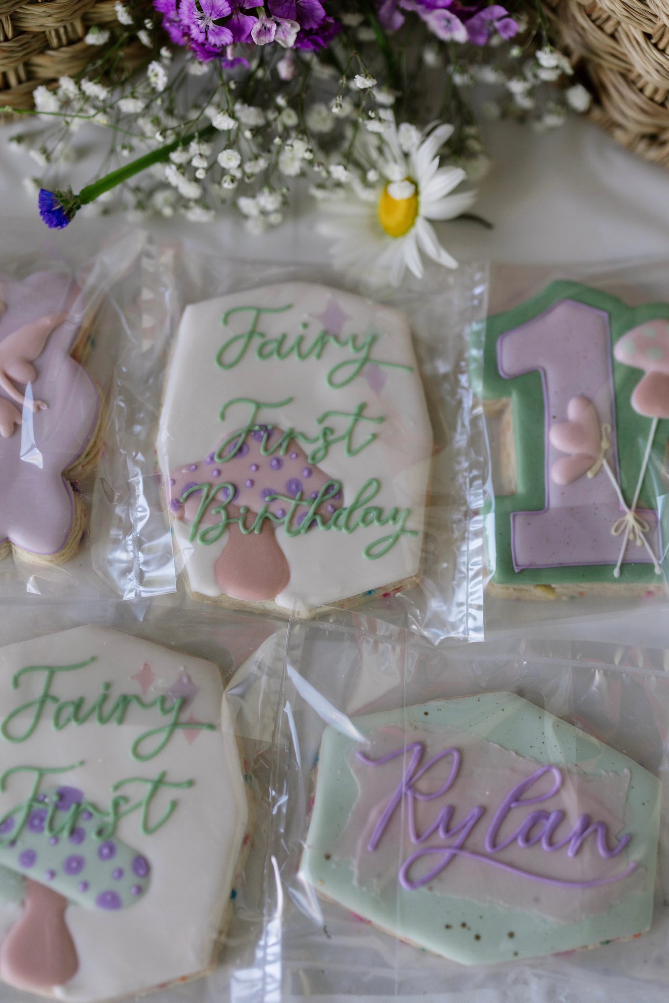 Individually wrapped custom sugar cookies decorated with fairy-themed motifs for a first birthday party.