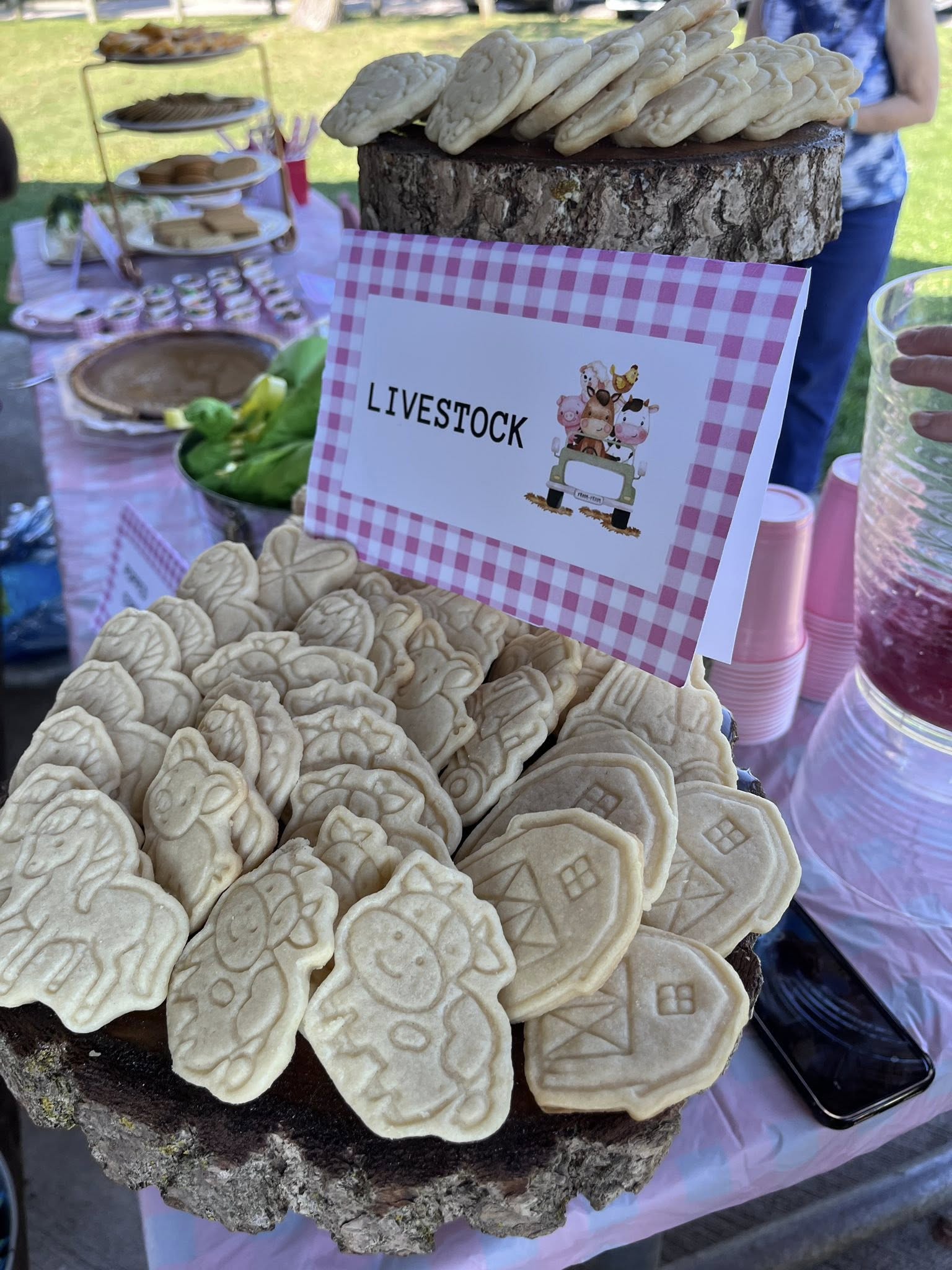 Platter of farm animal and barn-shaped sugar cookies with a Livestock sign on a wooden stand.