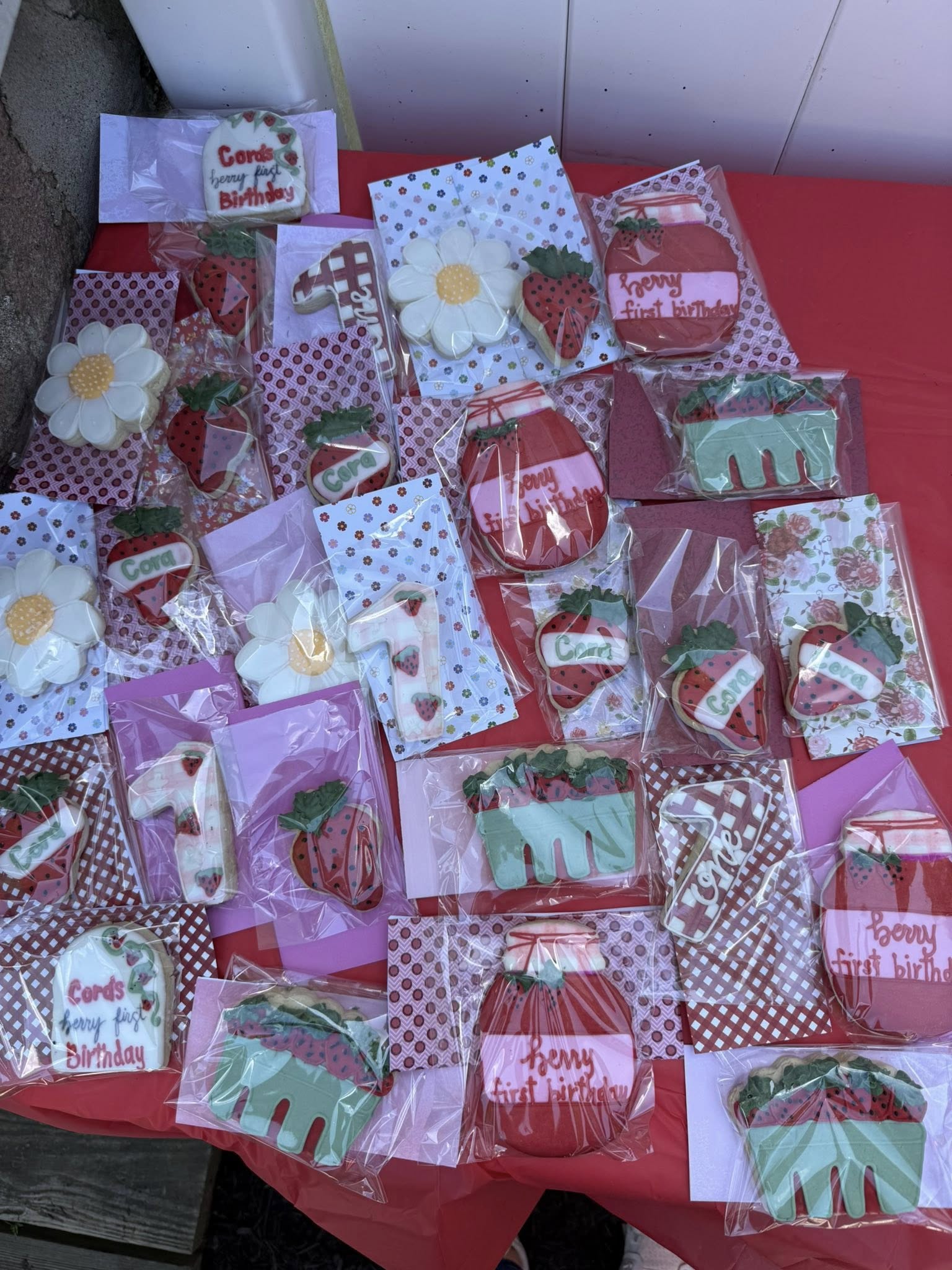 Custom strawberry-themed first birthday cookies featuring strawberries, daisy flowers, and the number one.