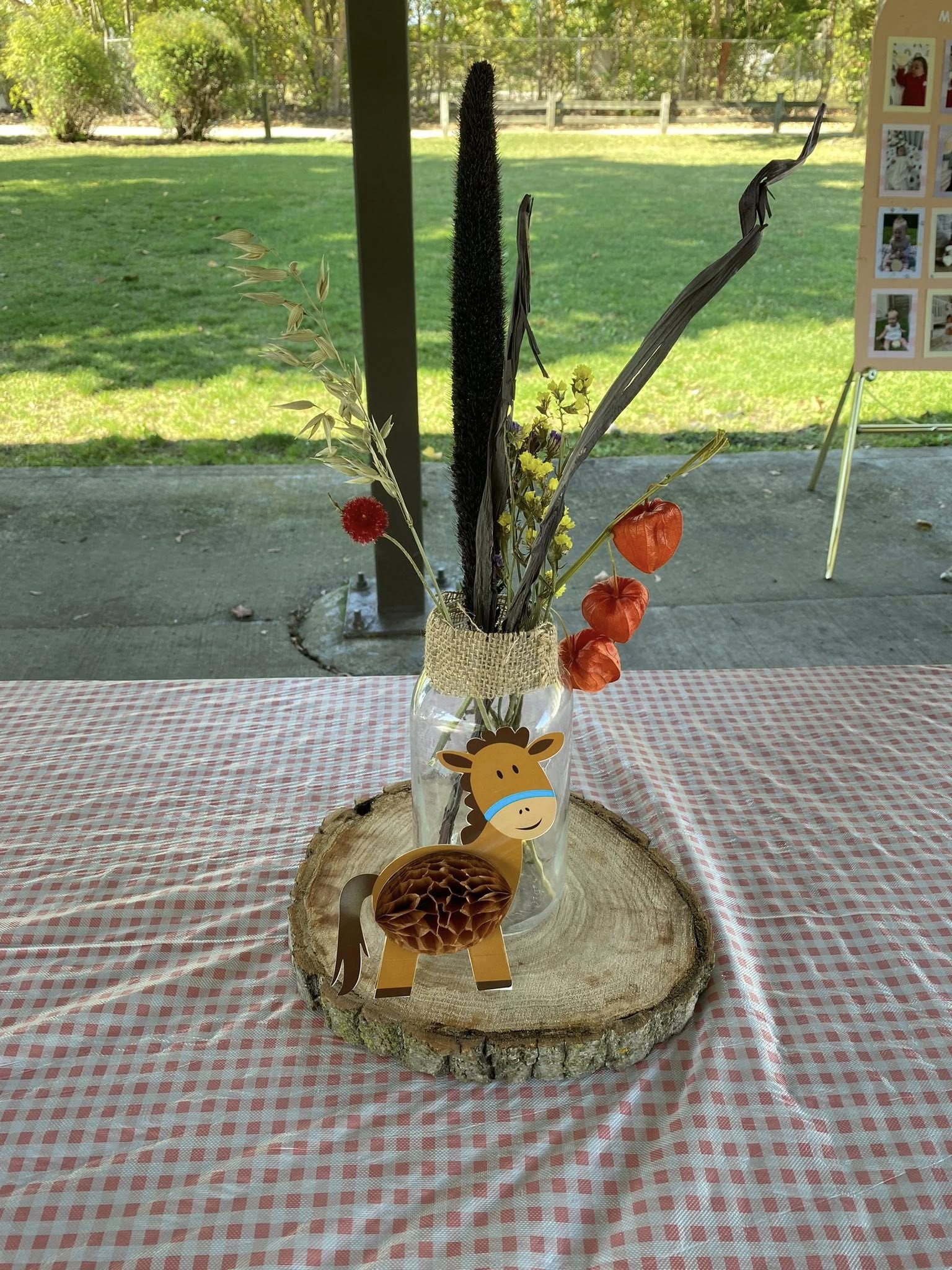 Table centerpiece with a rustic mason jar, dried floral arrangement, and a cute honeycombed horse cutout on a wood slice