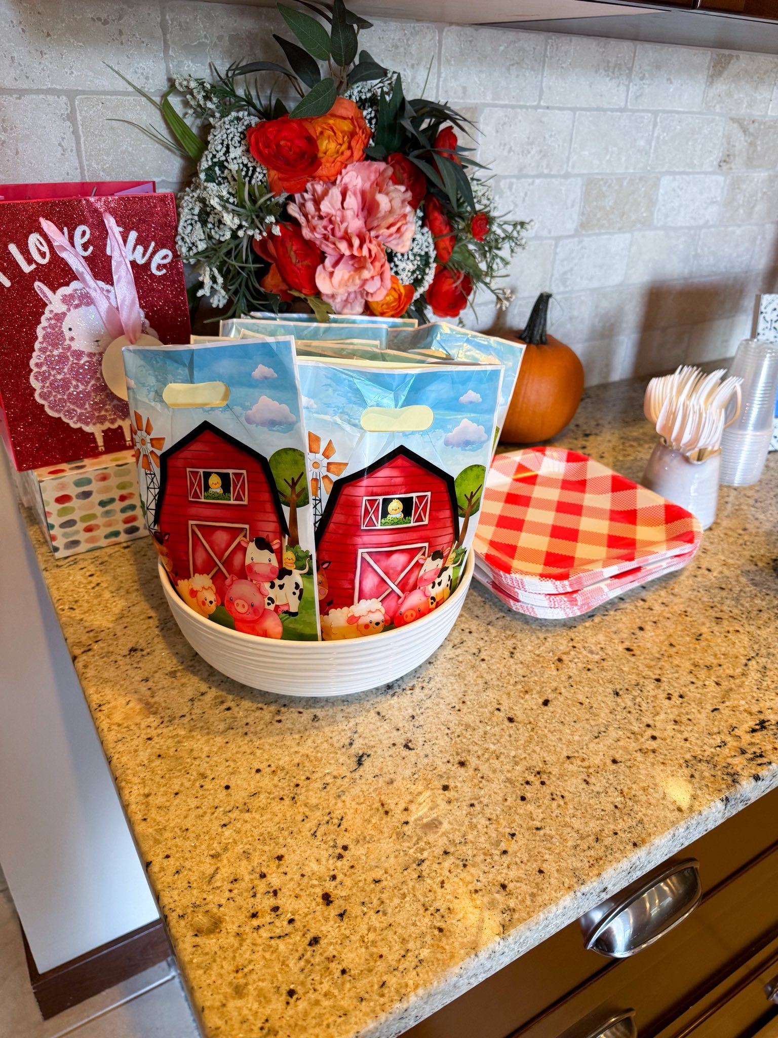 Set of barnyard-themed party favor bags displayed in a white bowl with red plaid paper plates