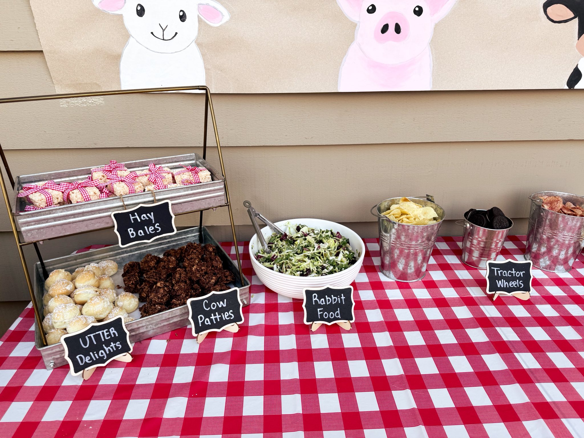 A farm themed party snack table with labeled treats including Hay Bales, Cow Patties, Rabbit Food, and Tractor Wheels.