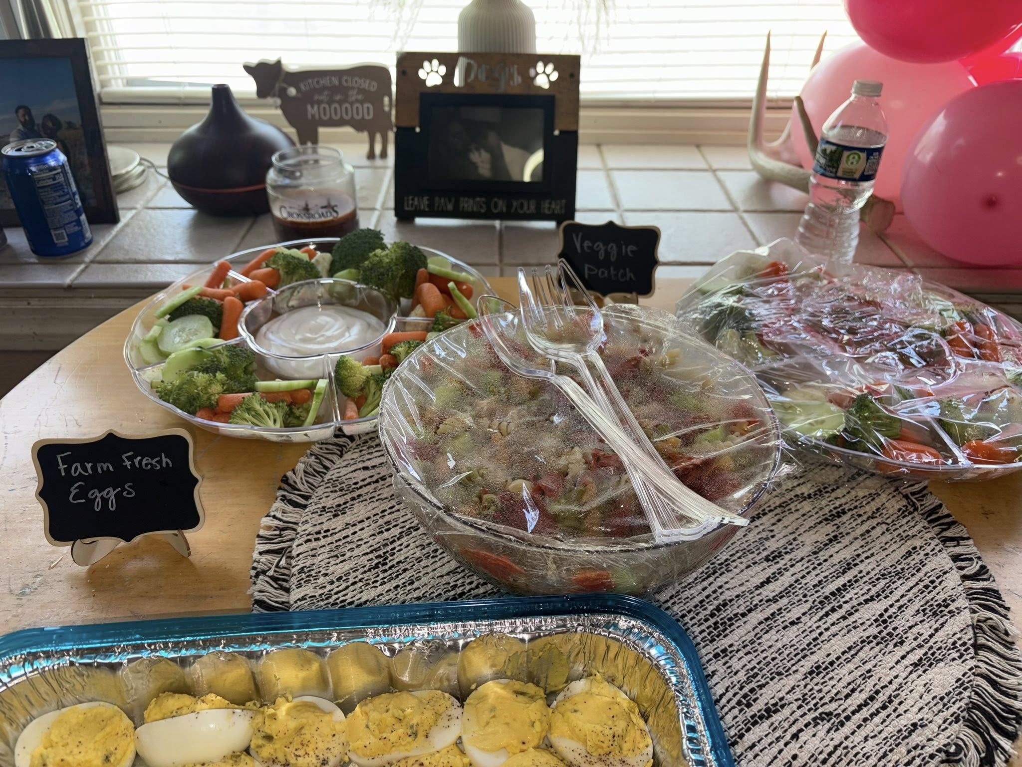 Table spread featuring a tray of fresh vegetables with dip, a bowl of pasta salad, and deviled eggs labeled Farm Fresh Eggs.