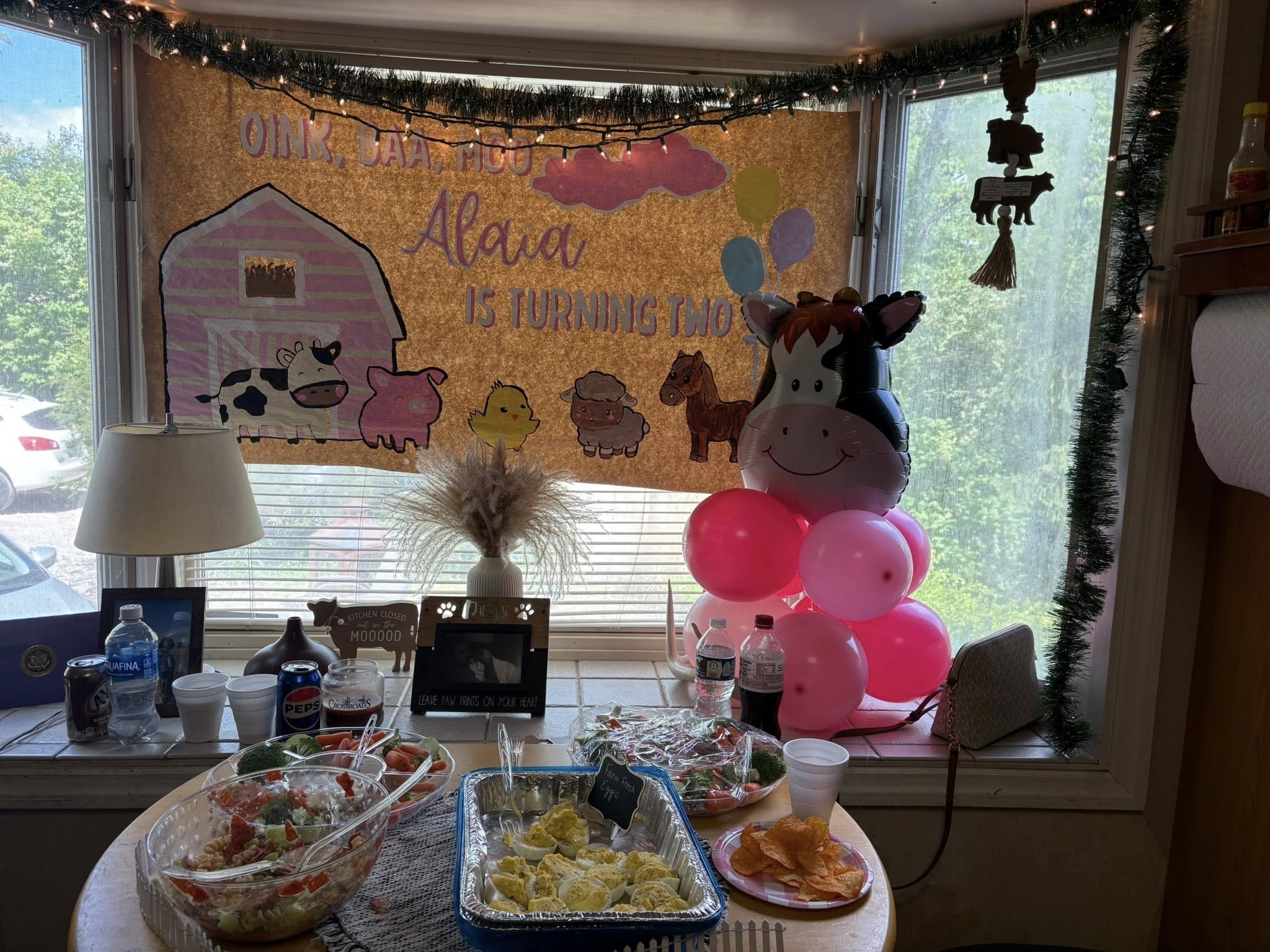 Barnyard themed second birthday party decorations with a banner, cow balloon, balloons, and buffet table