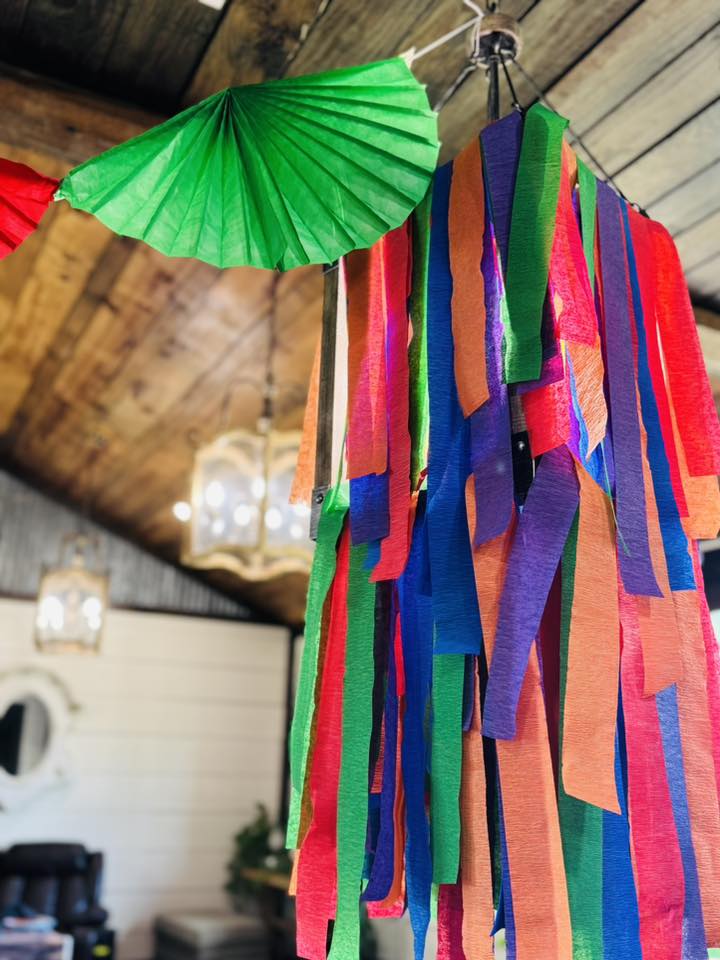 Colorful paper streamer decorations hanging from a ceiling in a rustic room.
