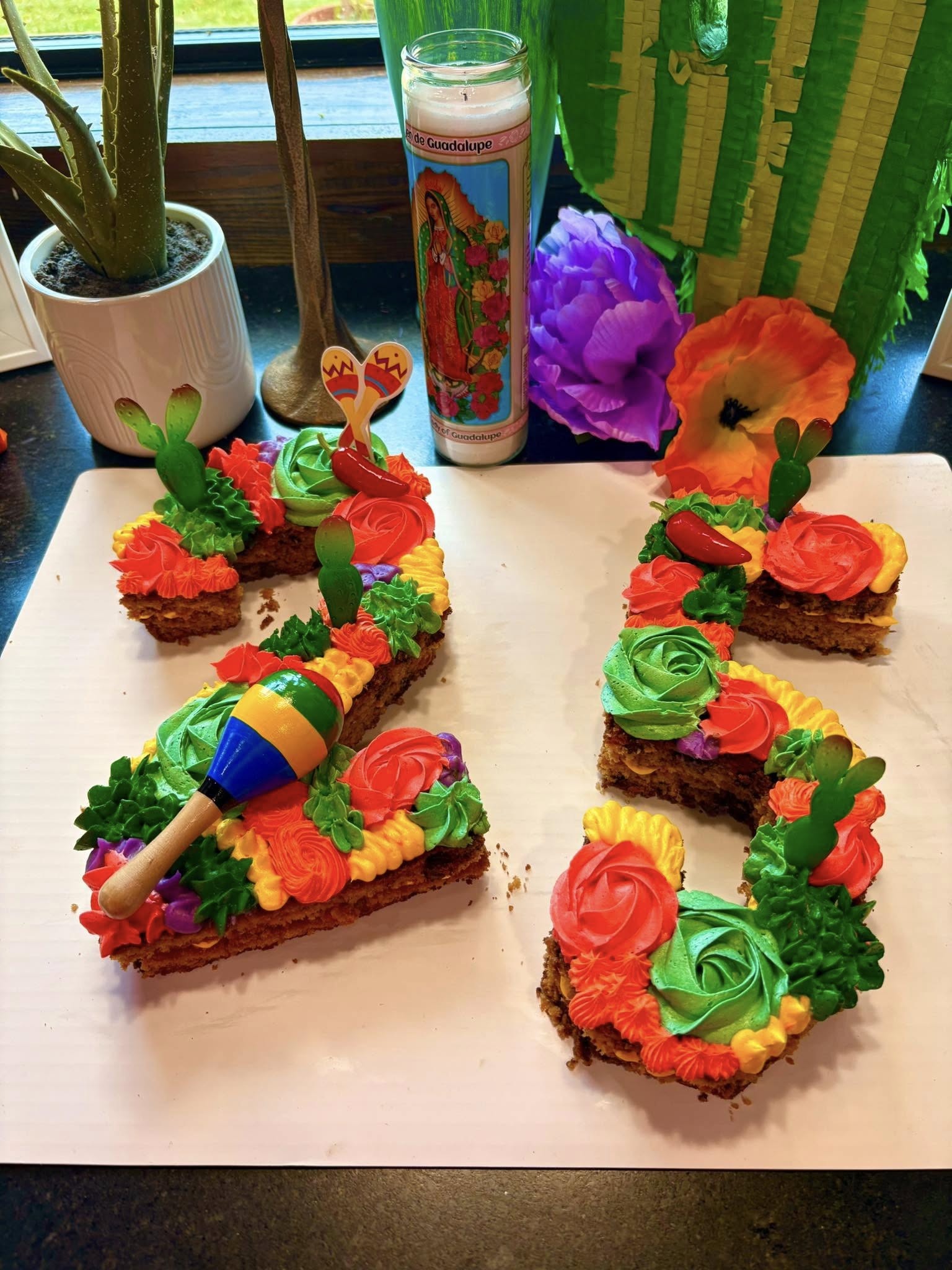 Number 25 cake decorated with bright fiesta-themed frosting, maracas, and miniature cactus toppers.