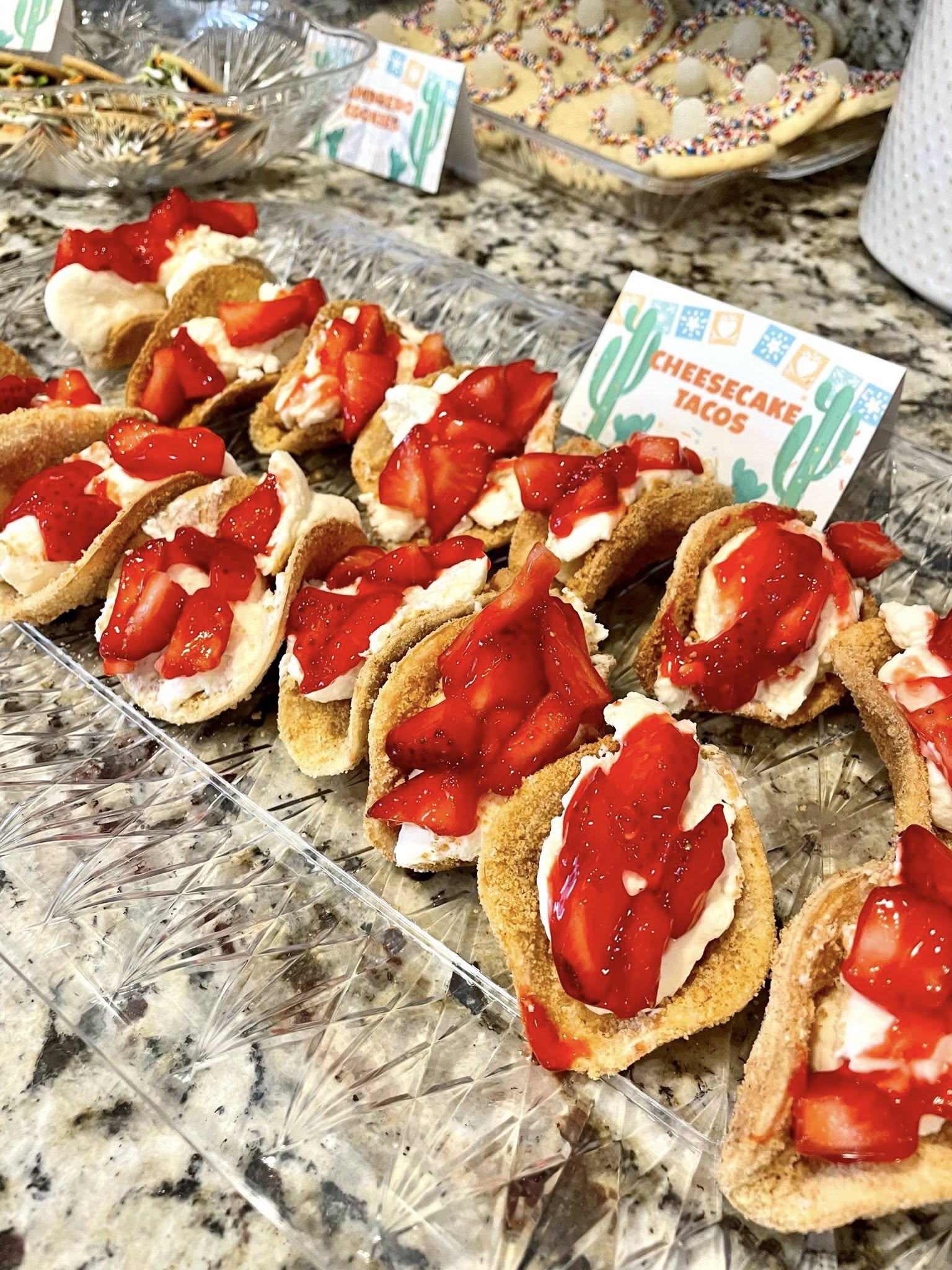 Platter of mini dessert tacos filled with cheesecake mousse and topped with fresh strawberries.