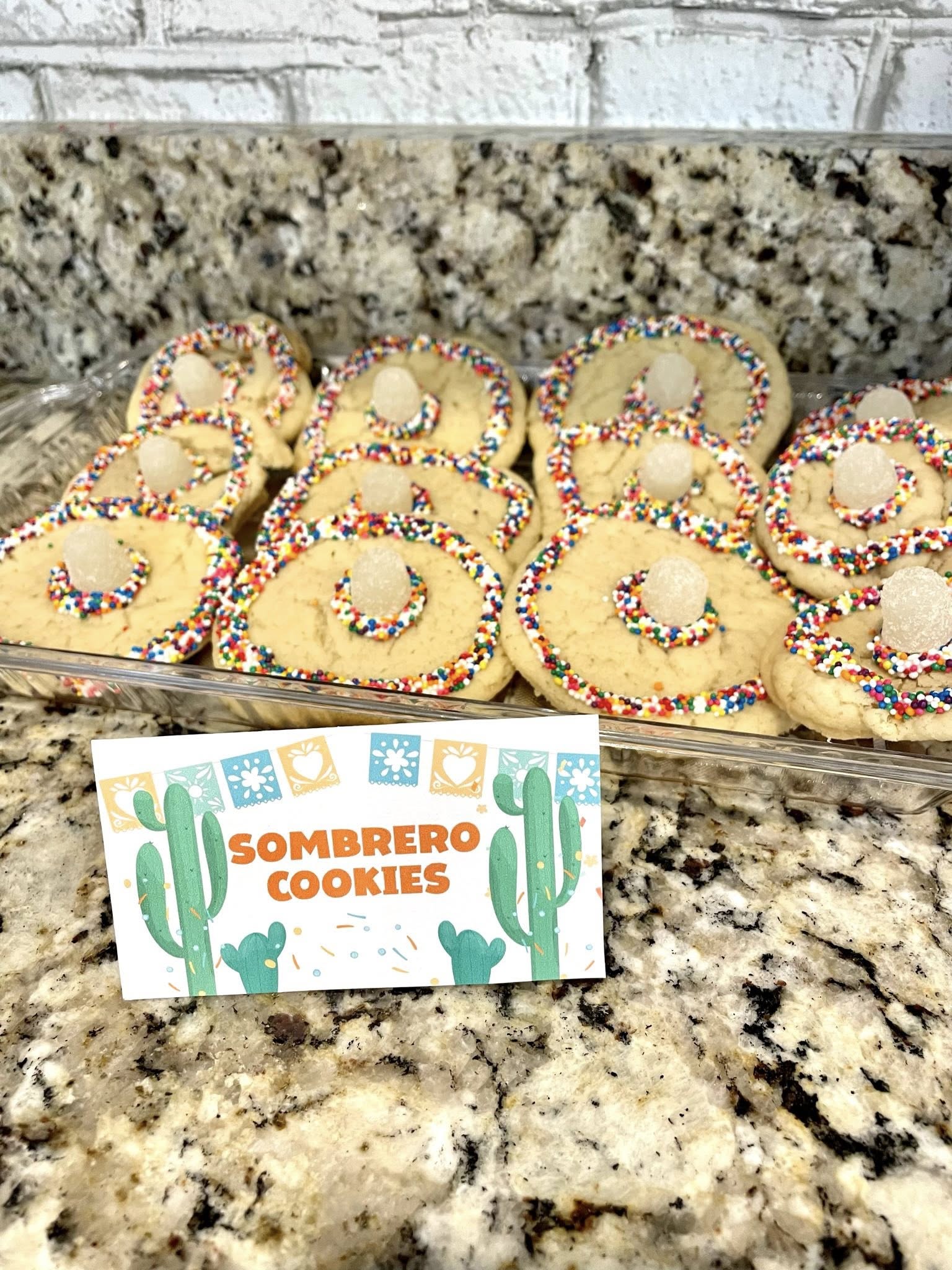 Tray of homemade sombrero-shaped sugar cookies decorated with rainbow sprinkles and gumdrop centers.