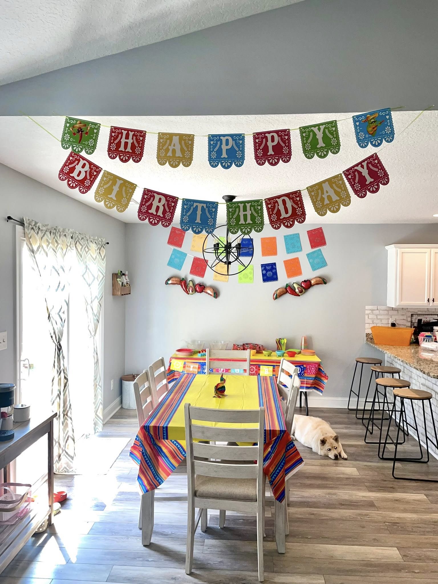 Dining room decorated for a fiesta-themed birthday party with festive paper banners and bright colors.