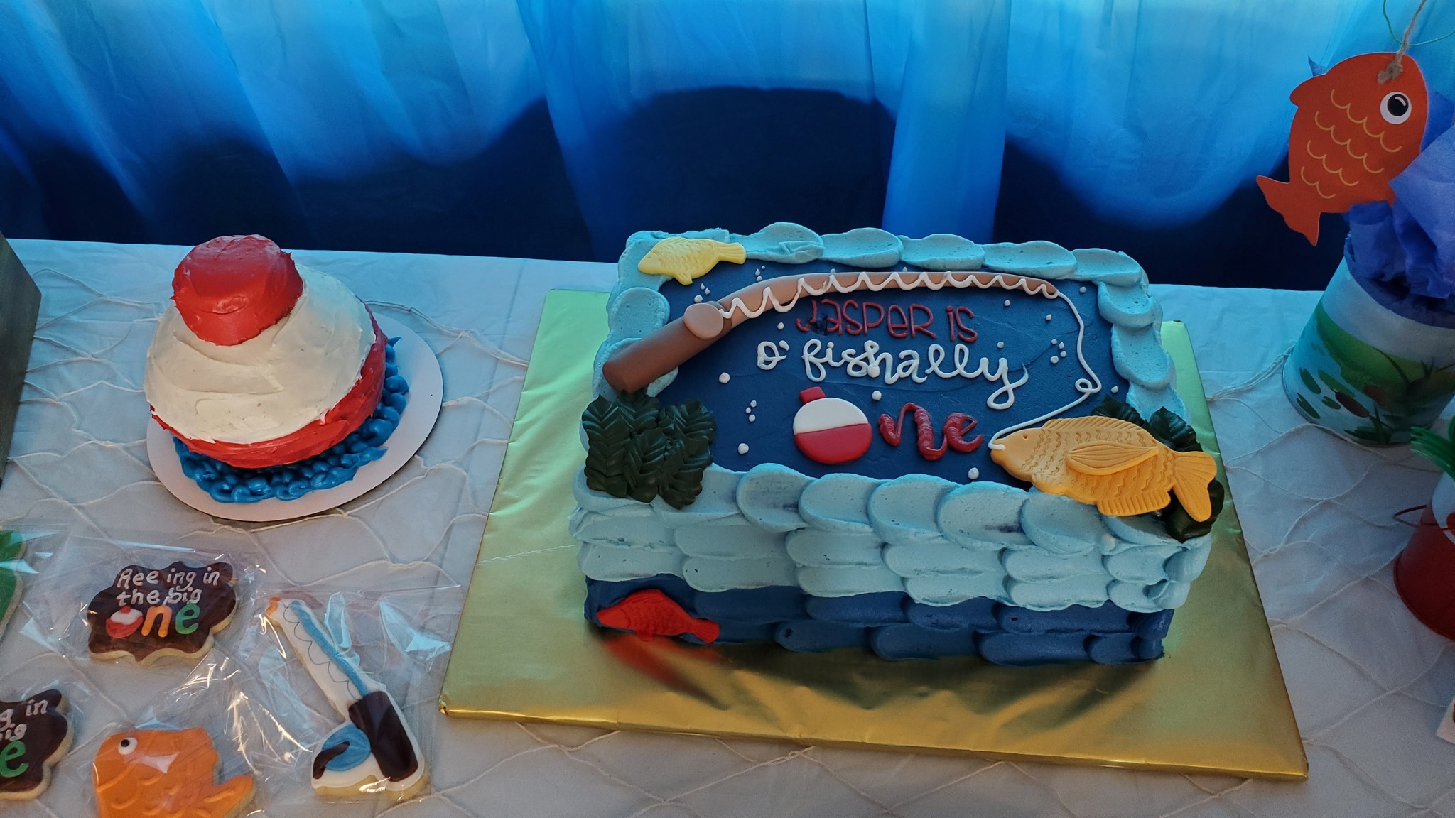 Rectangular blue fishing-themed first birthday cake with fish and bobber decorations