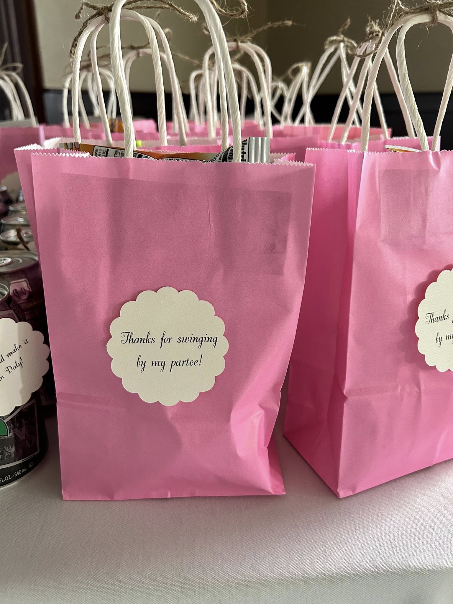 Group of pink paper favor bags with decorative labels reading Thanks for swinging by my partee!