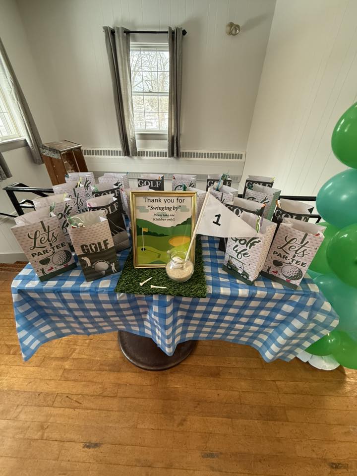 Golf-themed party favor bags on a blue checkered tablecloth with a Thank You sign for children.