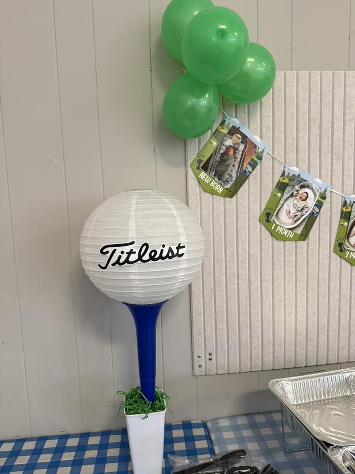 Titleist golf ball party centerpiece with green balloons and baby milestone photo banner