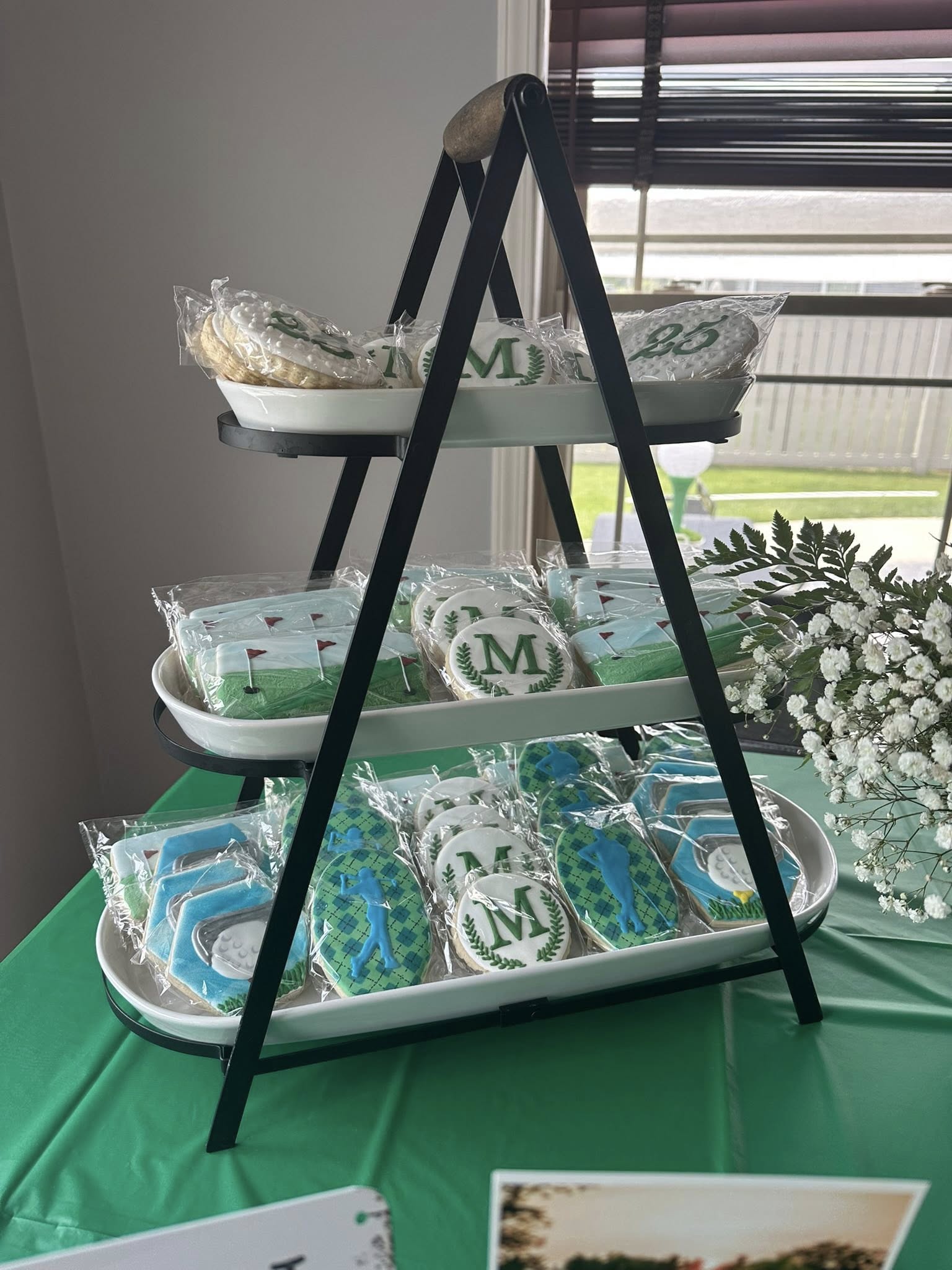 Three-tiered display stand featuring individually wrapped golf-themed sugar cookies for a party
