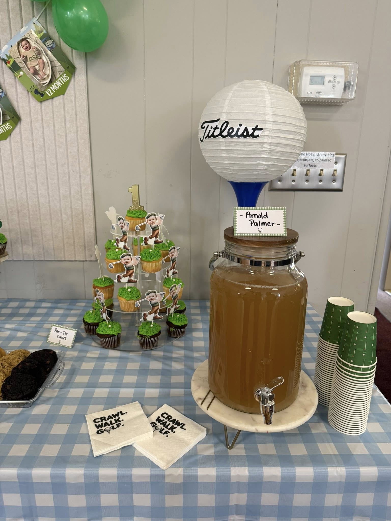 Golf-themed first birthday party table with Par-Tee cupcakes, Arnold Palmer drink dispenser, and festive napkins.