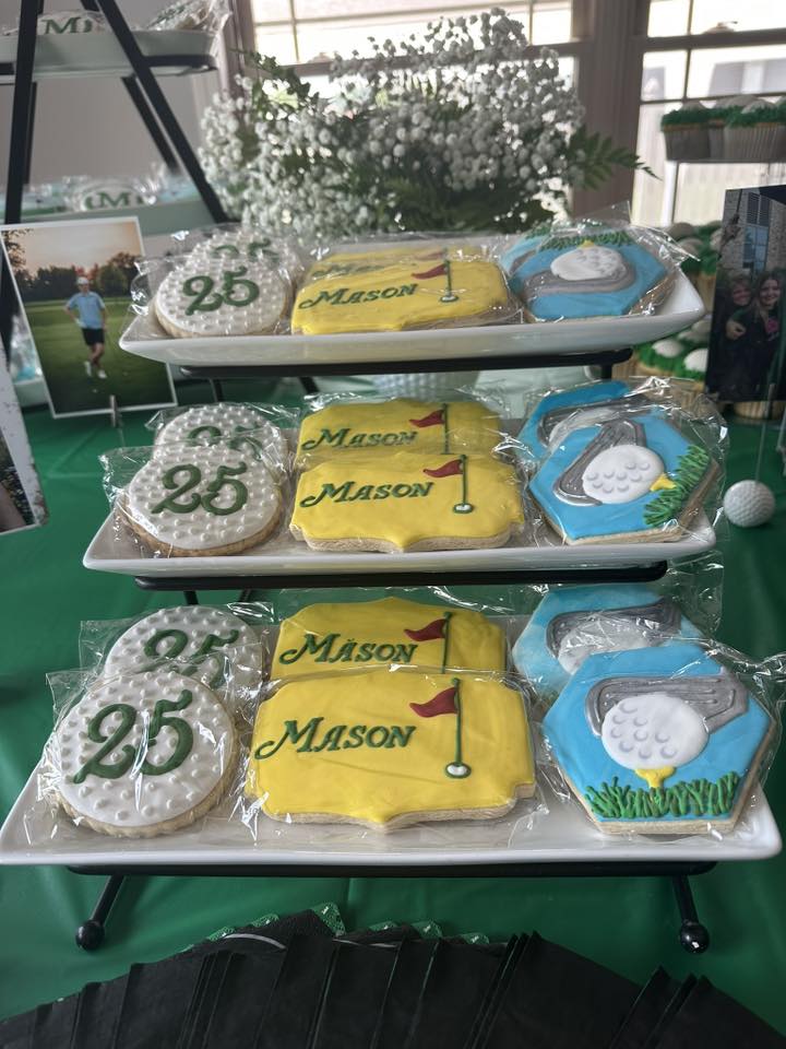 Golf-themed sugar cookies personalized with the name MASON and the number 25 arranged on tiered white serving trays.