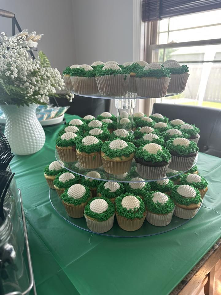 Cupcakes decorated to look like golf balls on a three-tier stand.