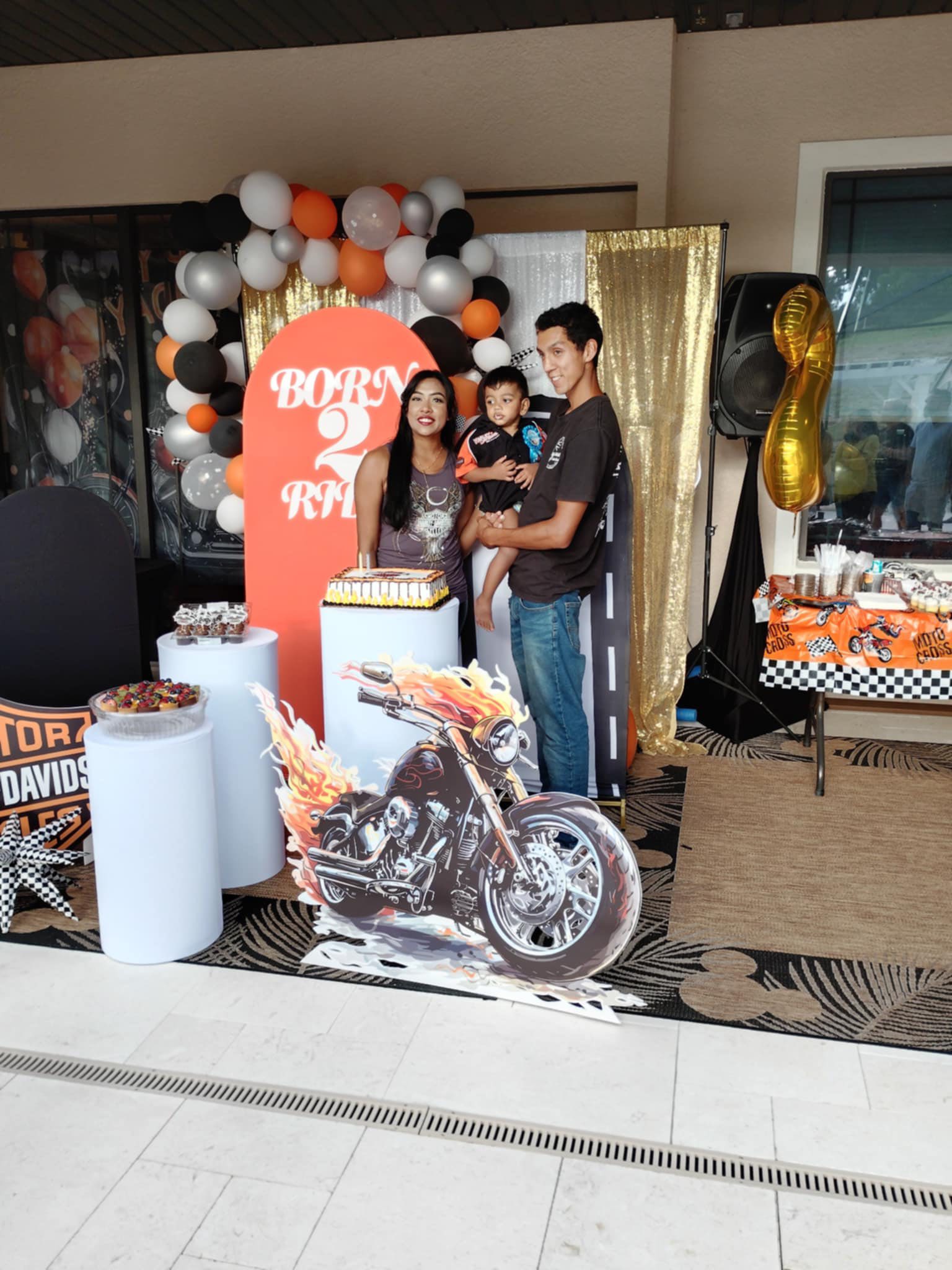 Family posing for a photo at a second birthday party with a Born to Ride motorcycle theme.
