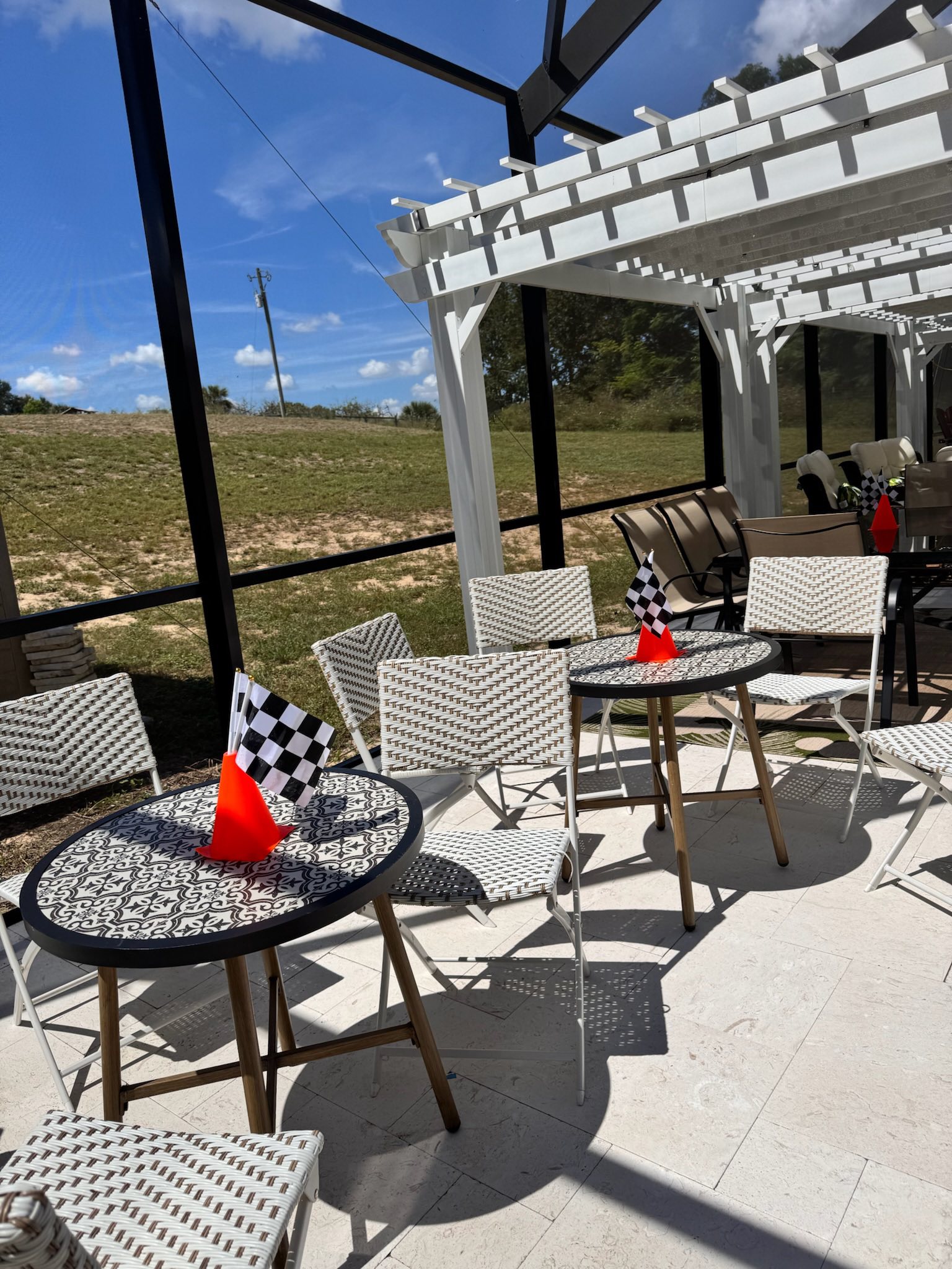Patio tables with checkered flags on orange cones at a sunny outdoor seating area.